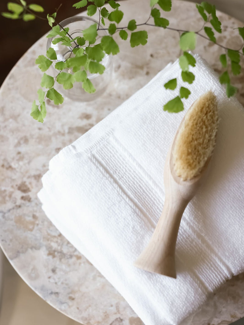 White washcloths folded on small table with brush