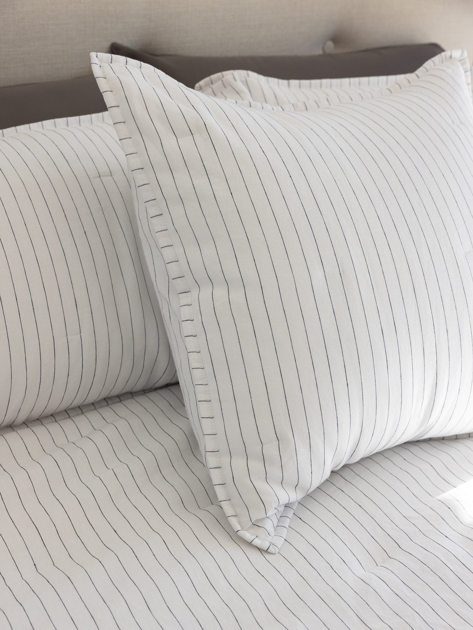 Close up of charcoal pencil stripe shams on bed 