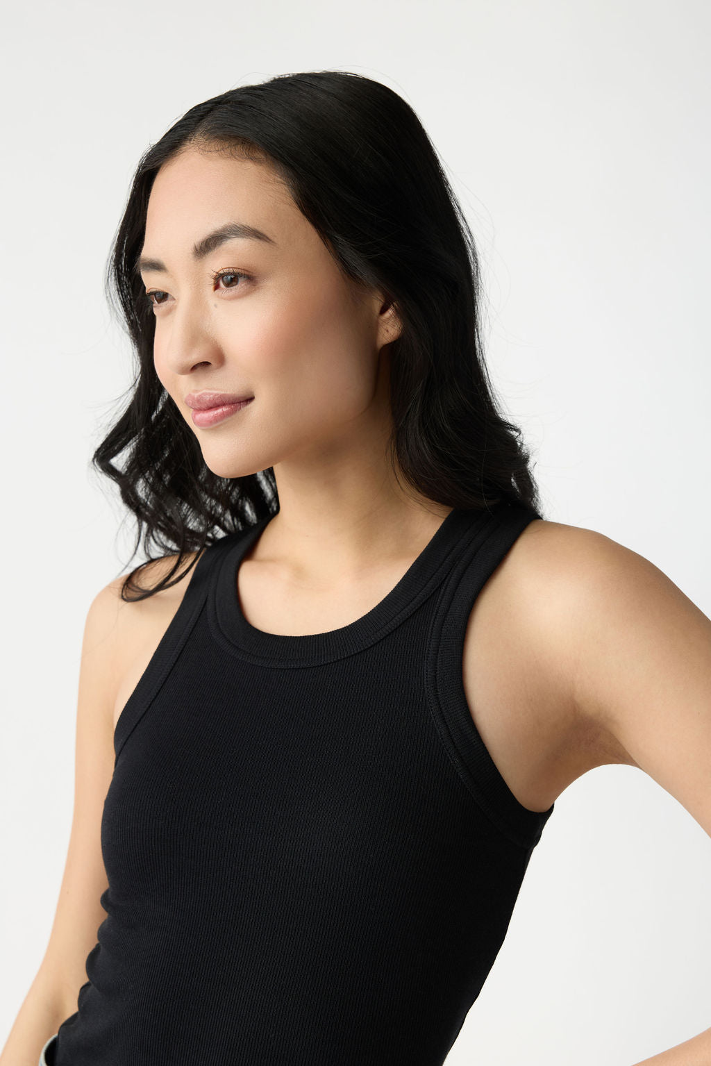 A closeup of the shoulder straps and front of Cozy Earth Women's Fine Ribbed Tank in Jet Black on a dark haired woman. 