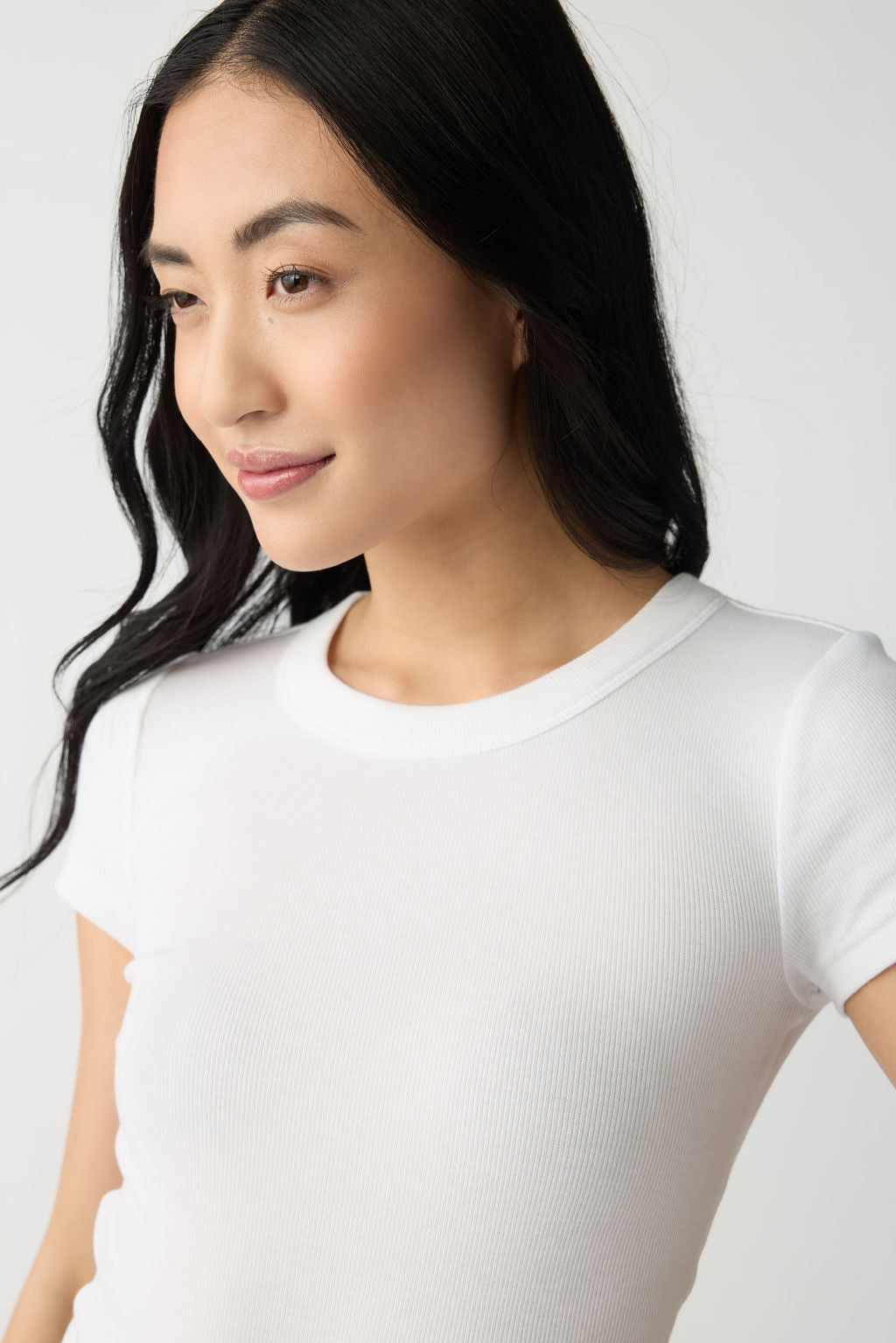 A dark haired woman wears Cozy Earth Women's Fine Ribbed Tee in White. She is pictured from the chest up. |Color:White