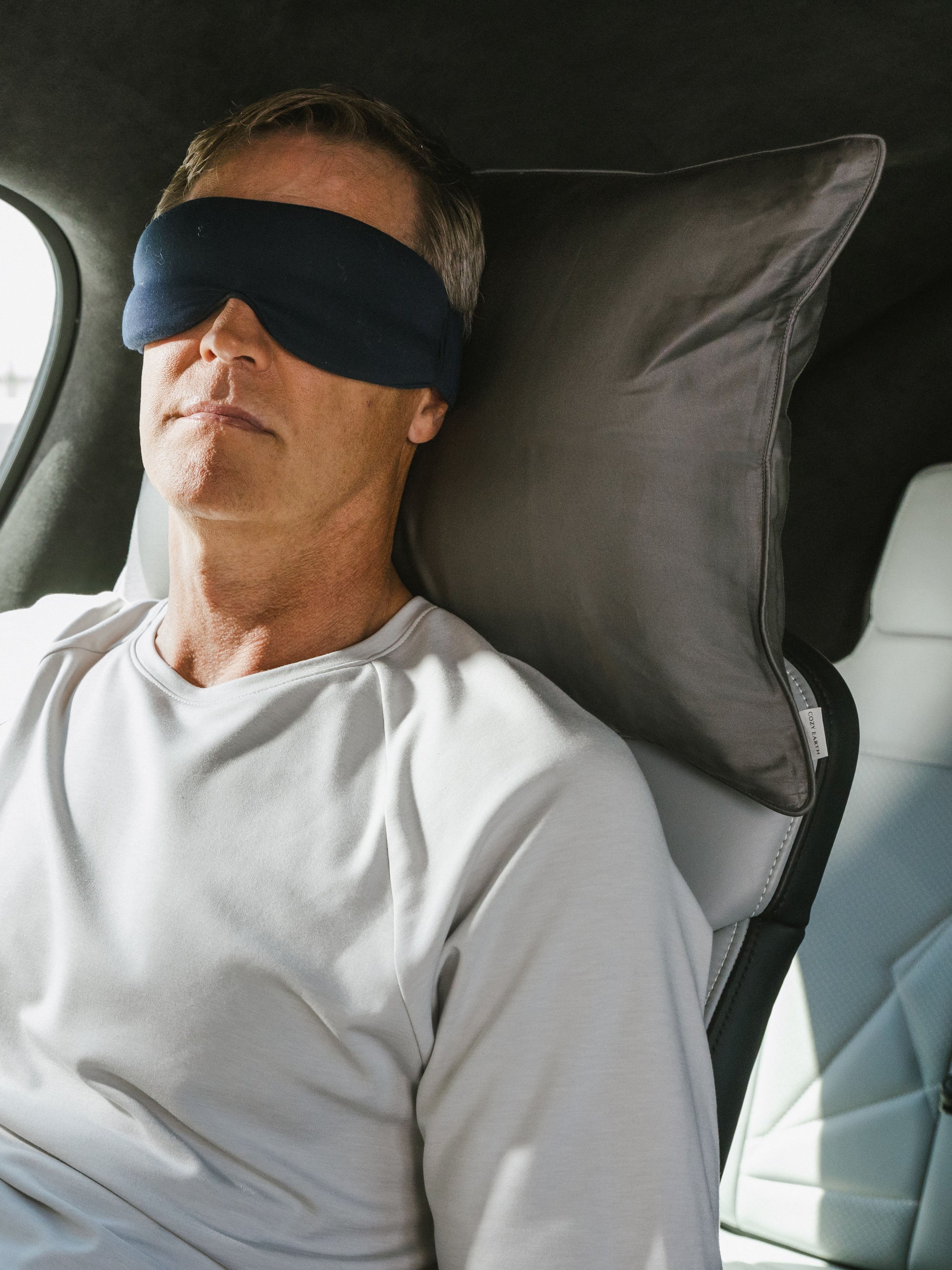 Man with face mask in airplane using travel pillow 