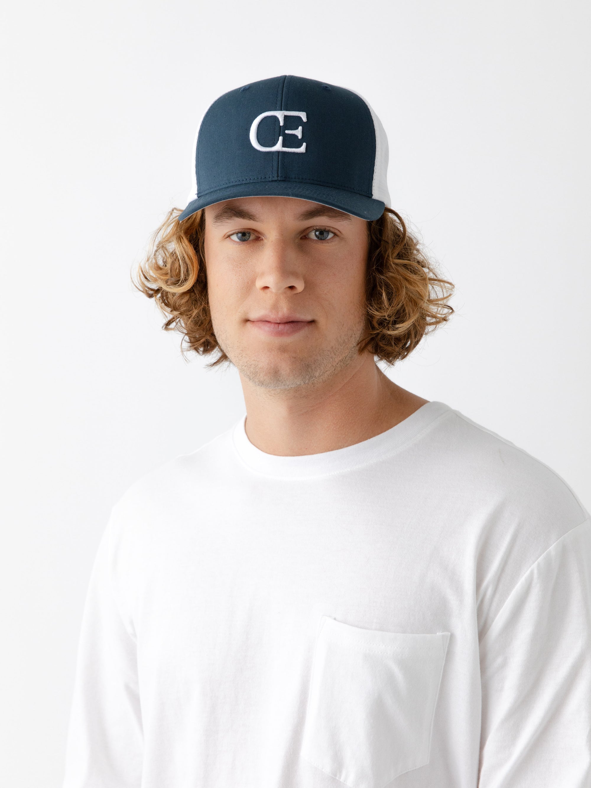 Man wearing a Navy and white cap with a CE logo on a light gray background 