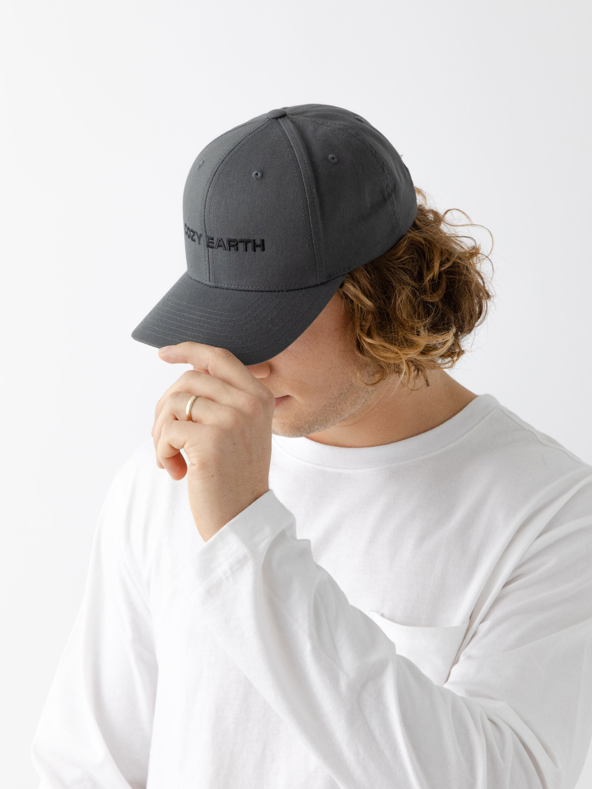 A man wearing a grey cap with 'COZY EARTH' text on a white background 