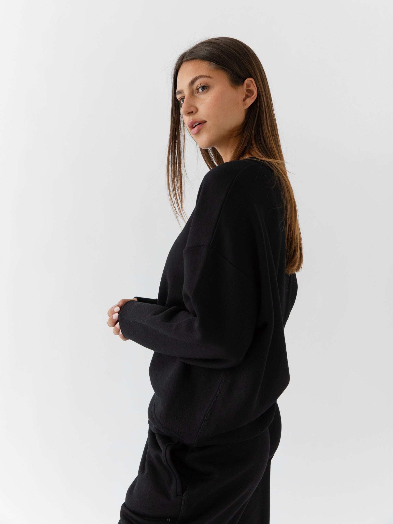 Black CityScape Pullover Crew. The Pullover is being worn by a female model. Accompanying city scape clothing is being worn to complete the look of the outfit. The photo was taken with a white background. 