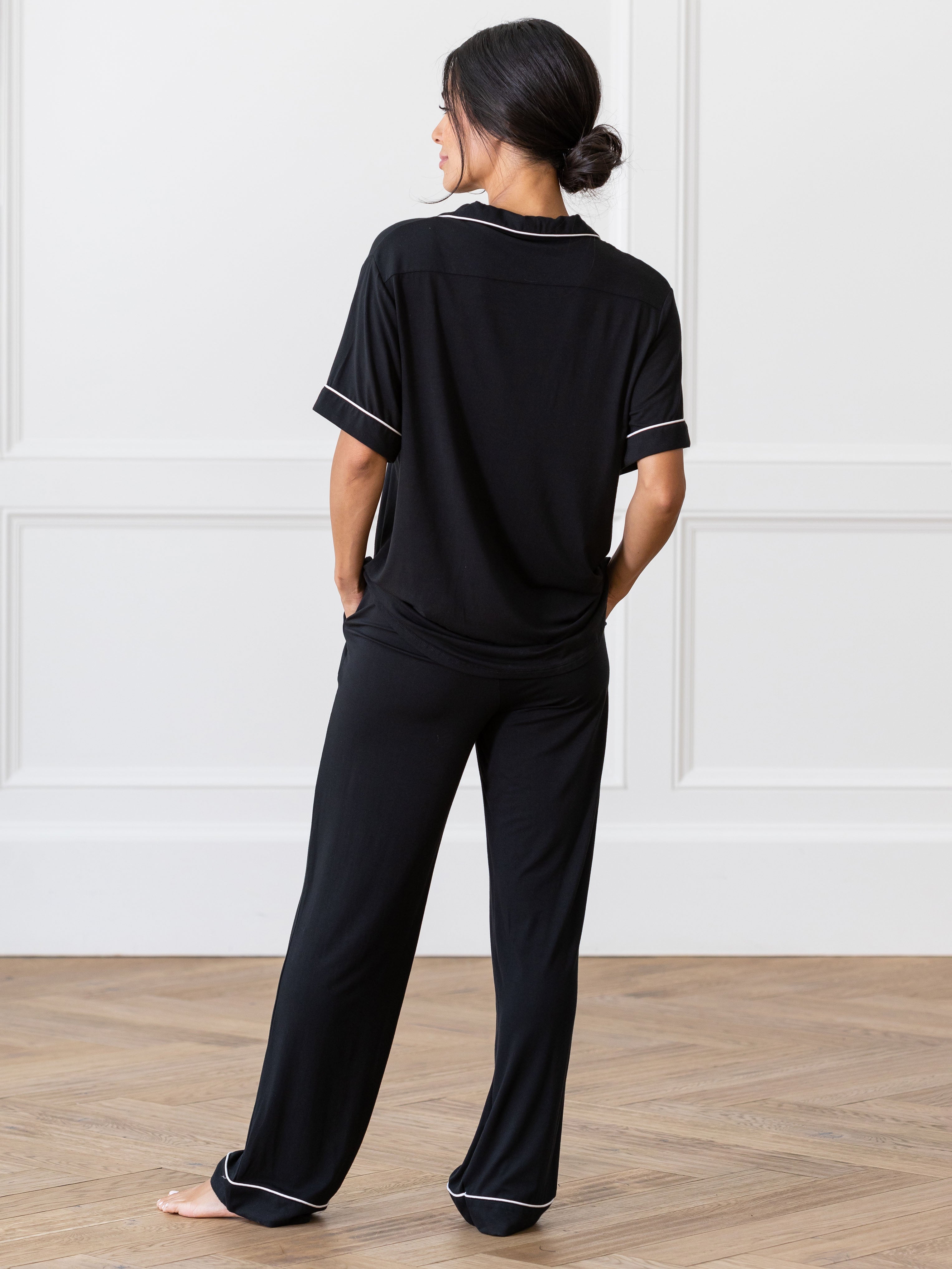 Black Short Sleeve & Pant Bamboo Pajama Set modeled by a woman. The photo was taken in a high contrast setting, showing off the colors and lines of the pajamas. |Color: Black