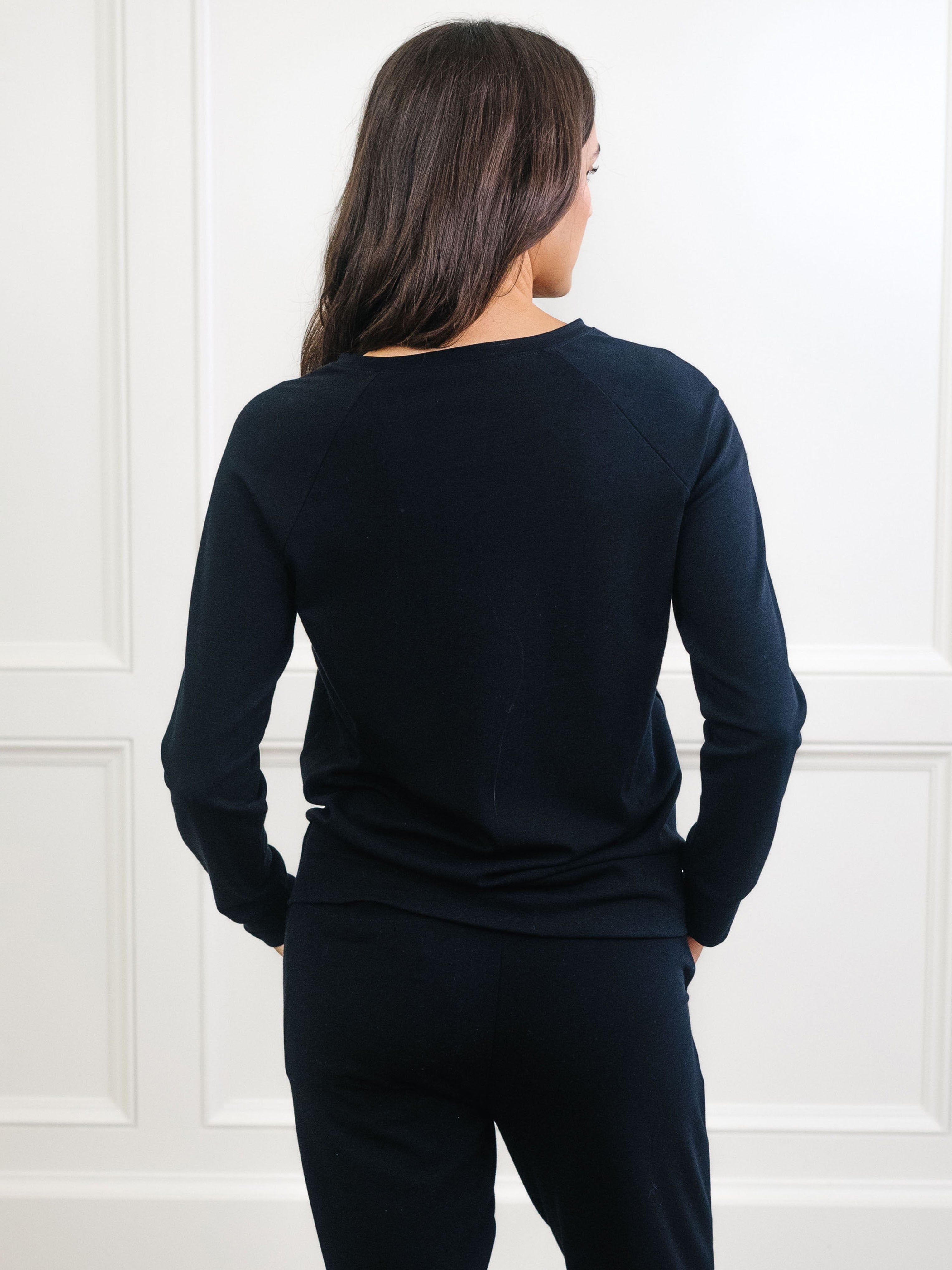Black Bamboo Jogger Set modeled by a woman. The photo was taken in a high contrast setting, showing off the colors and lines of the pajamas. 