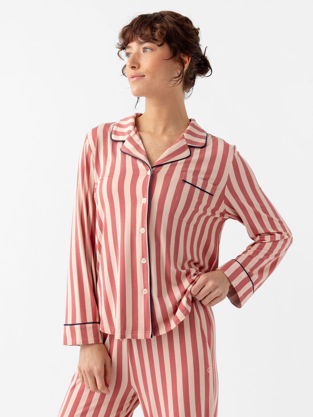Waist up of woman wearing blush stripe pajamas with white background 