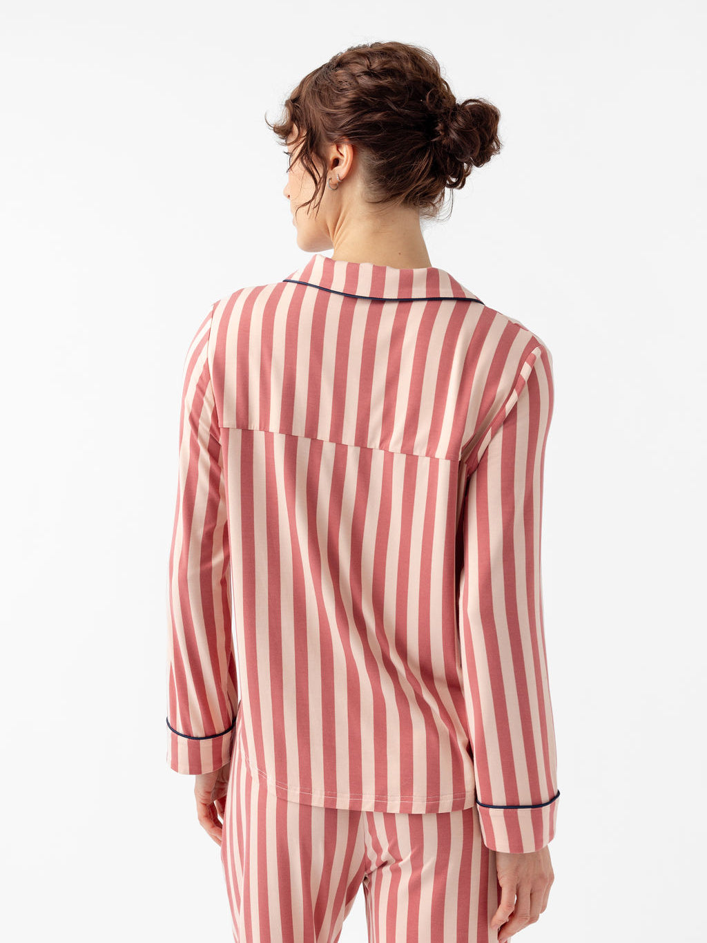 Back of woman wearing long sleeve blush stripe pajama top with white background 
