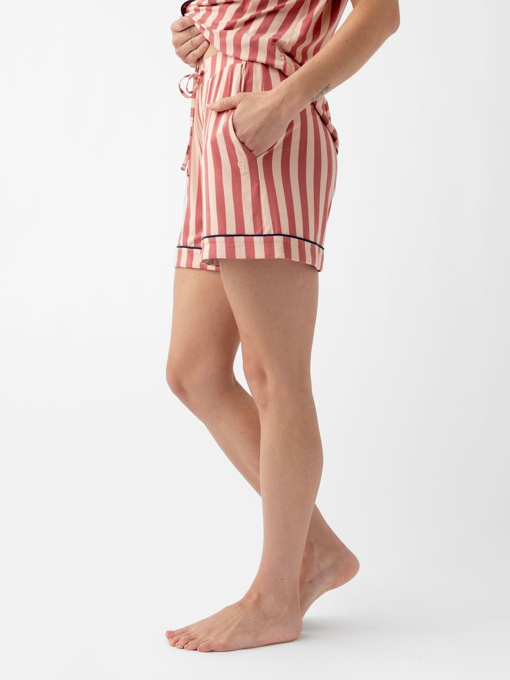 Woman wearing blush stripe pajama shorts with white background 