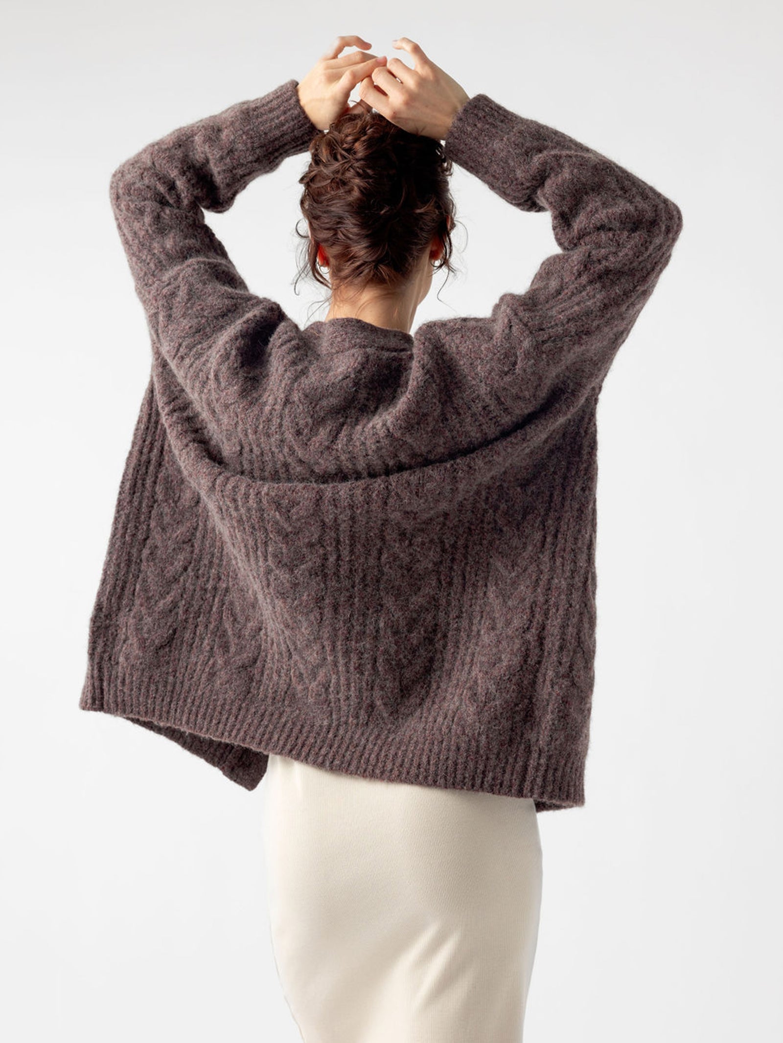 Back of woman wearing bordeaux cardigan with her arms up 