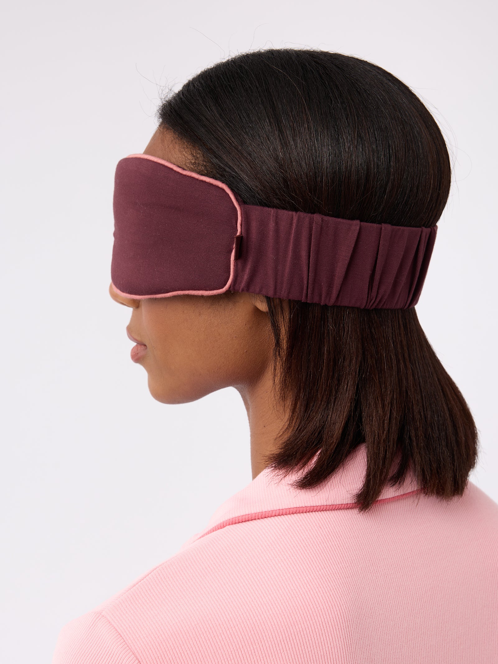 Side view of woman wearing burgundy sleep mask 