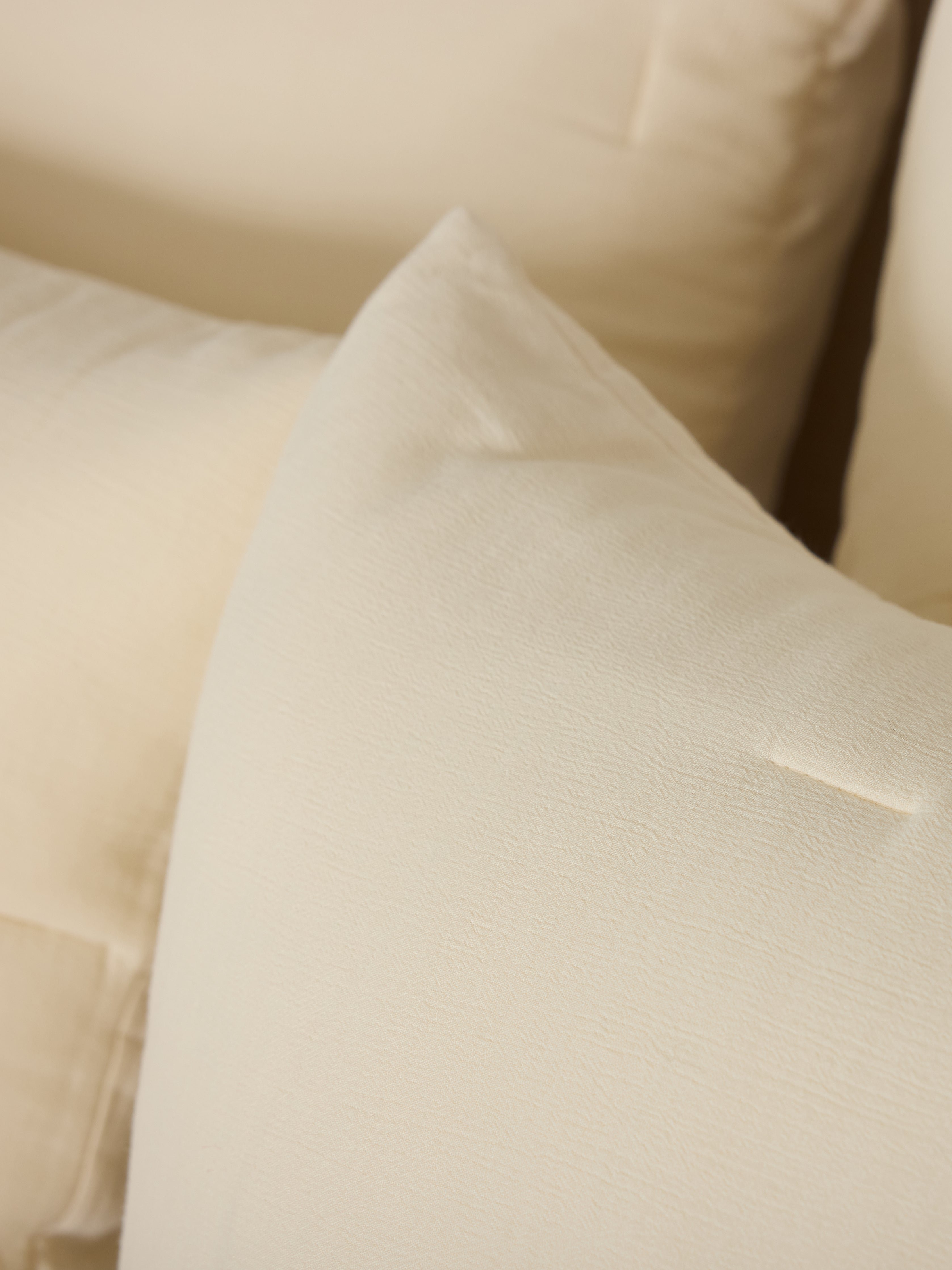 Close up of Buttermilk Aire Bamboo Puckered Shams. The shams are resting on a bed in a bedroom