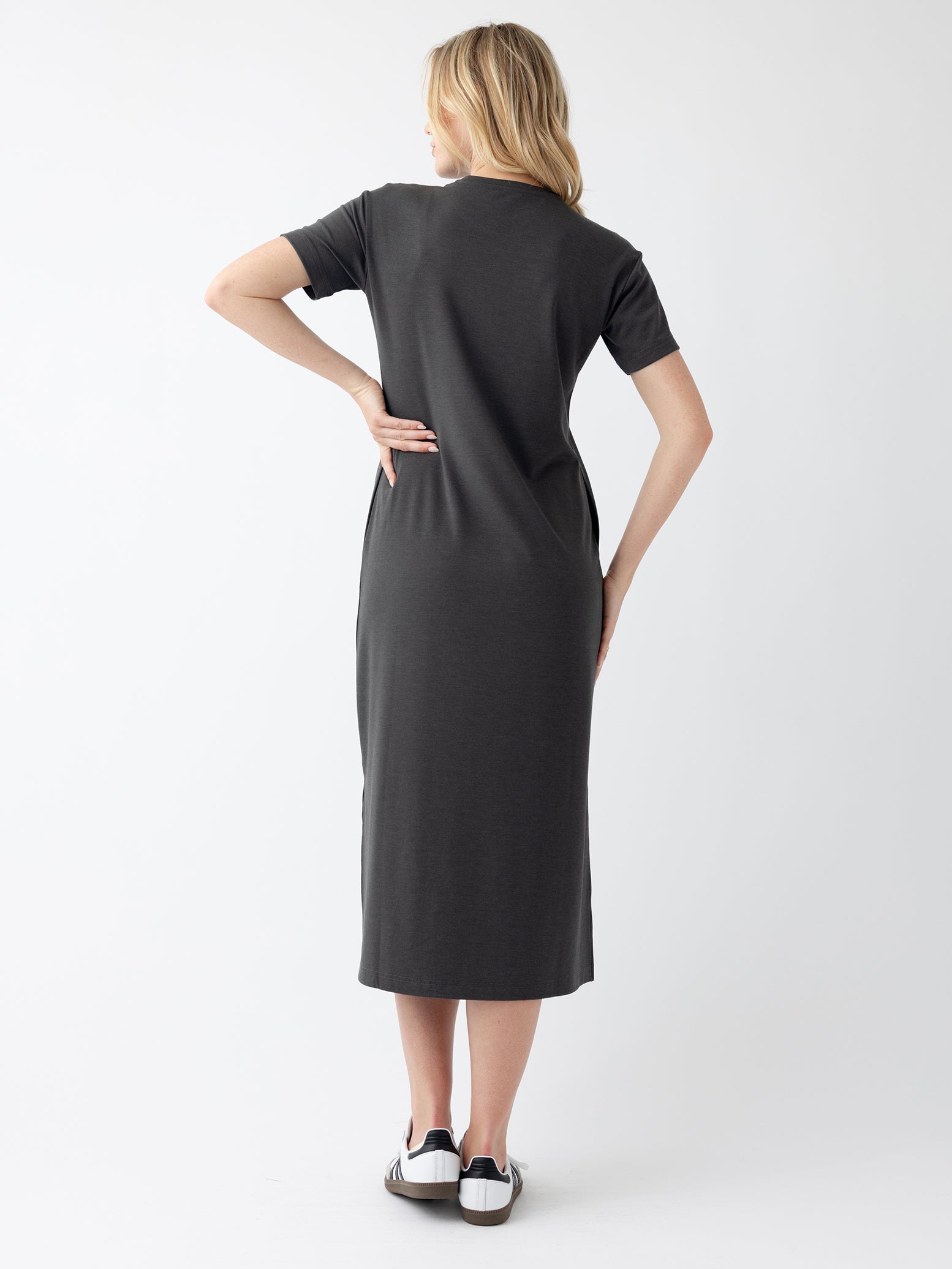 Back of woman in charcoal midi dress with white background 