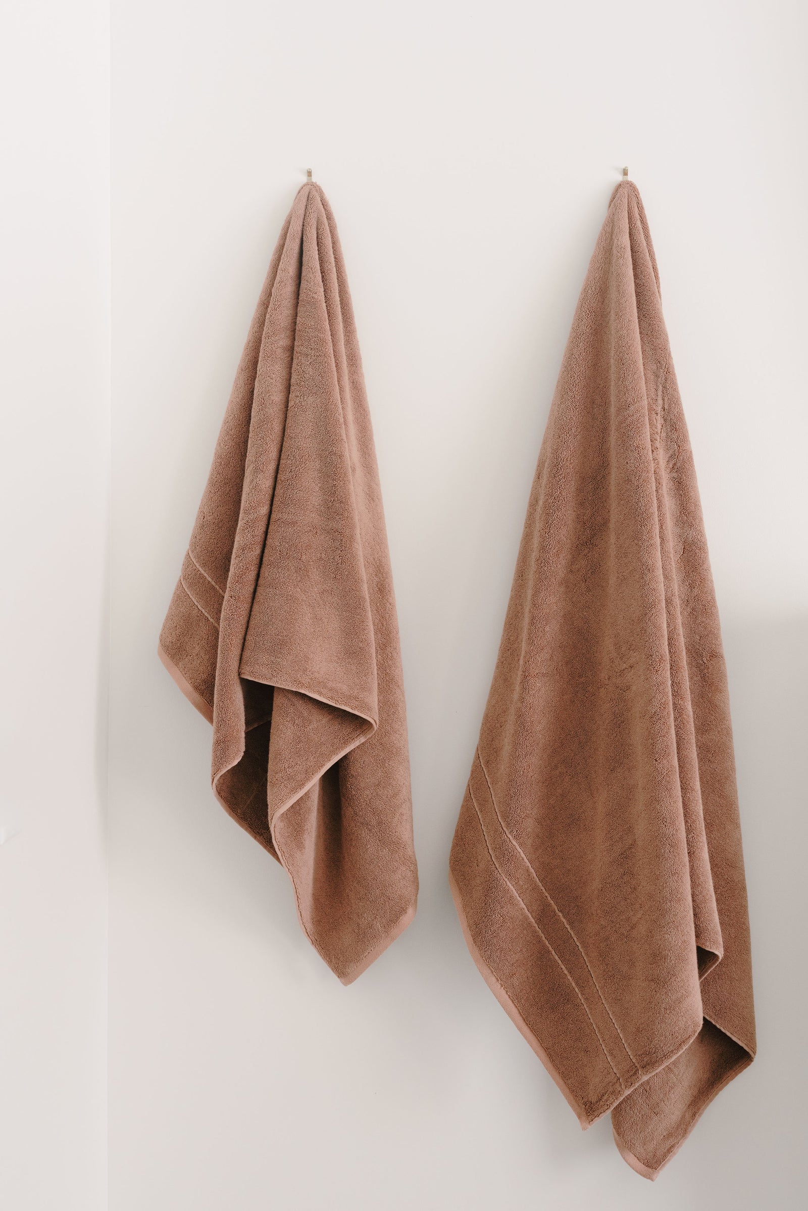 Premium Plush Bath Sheets in the color clay. Photo of Premium Plush Bath sheets/towels taken in a bathroom showing the towels which are hung from a towel rack. 