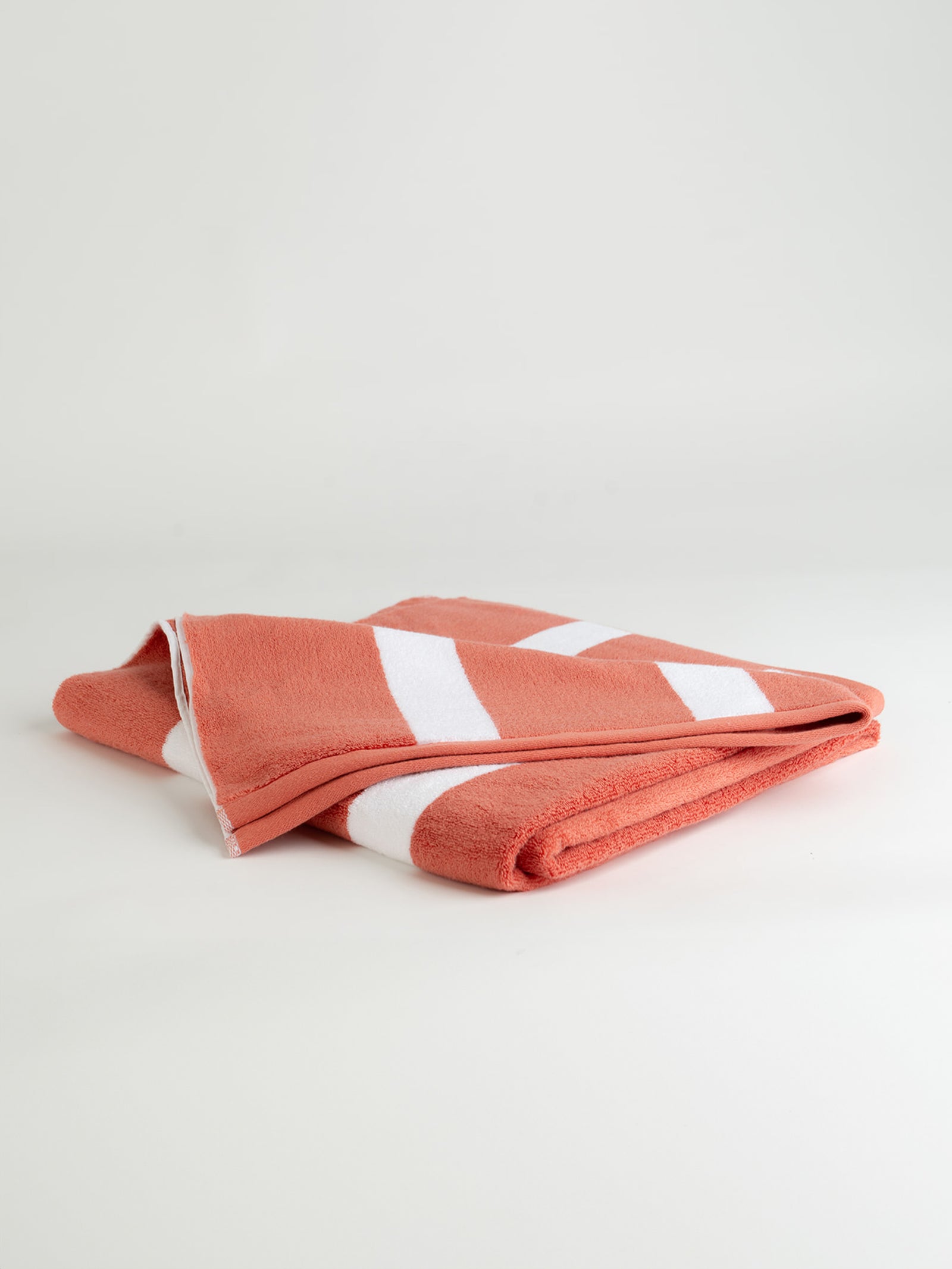 Coral resort towel folded with a white background 
