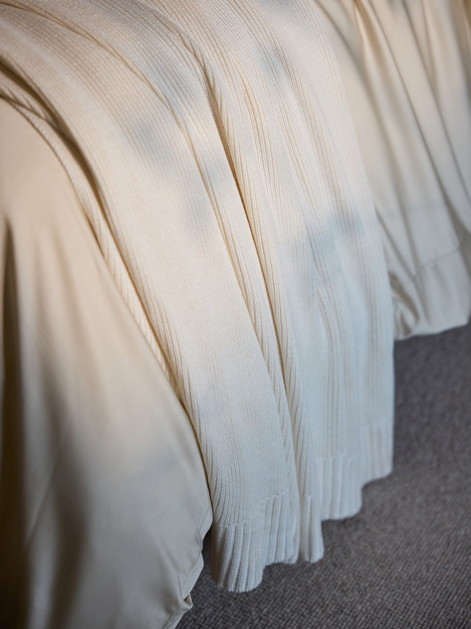 Creme Classic Knit Blanket draped over a bed. 