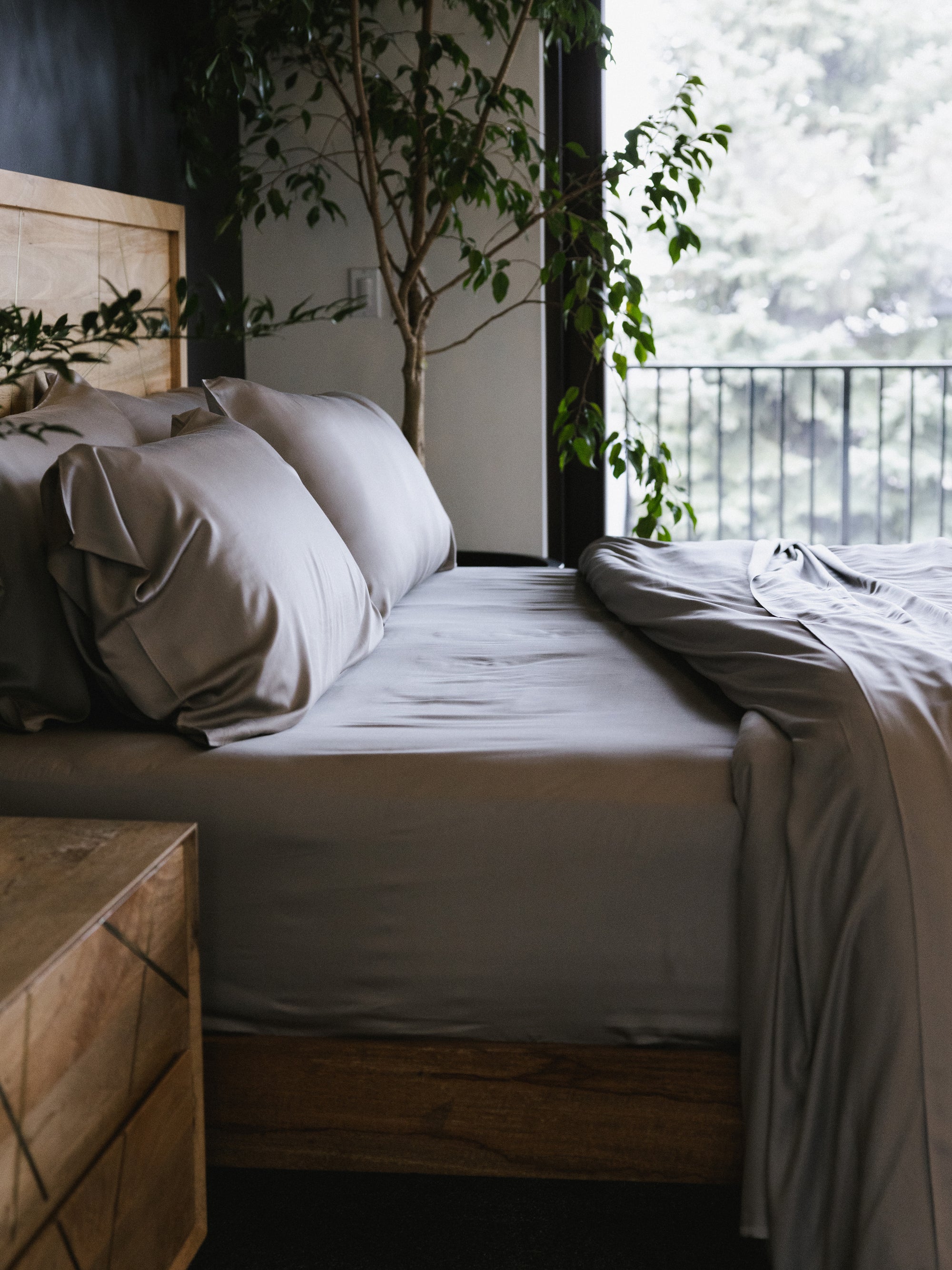 Side view of bed with dove grey sheets and comforter pulled off the top 