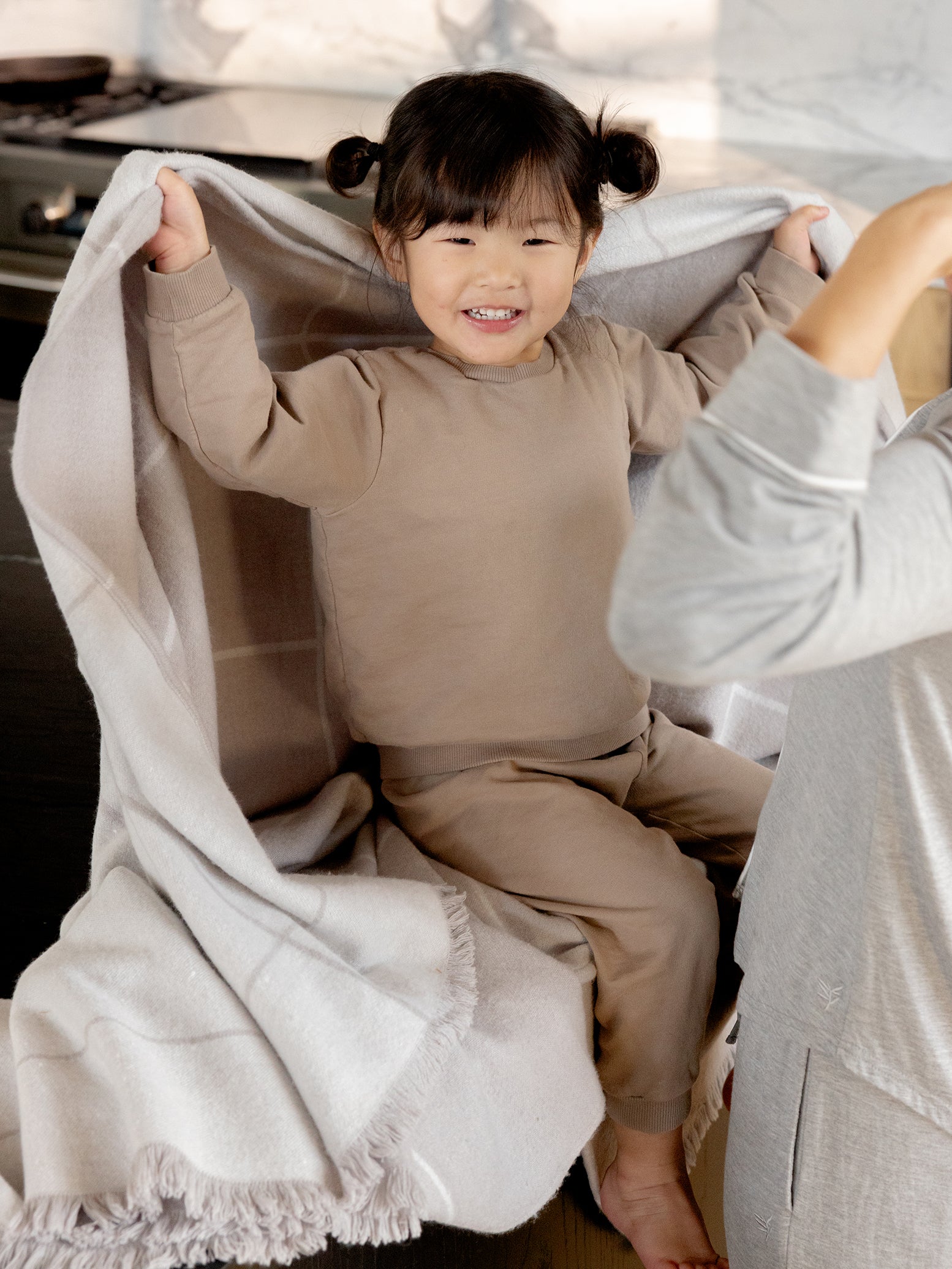 Little girl holding grey windowpane blanket 