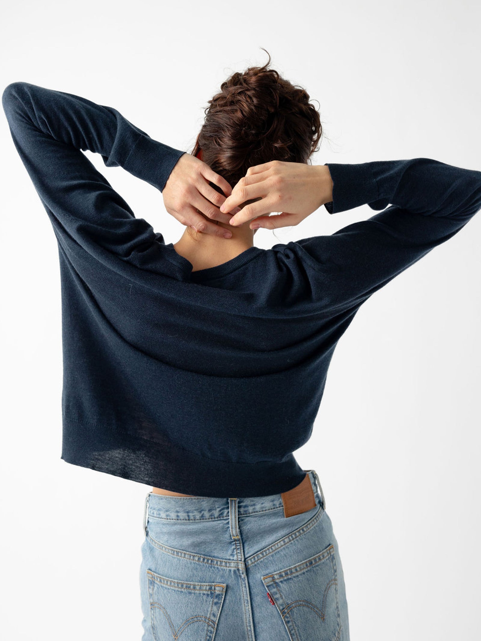Back of woman wearing jeans and an eclipse airknit sweater with white background 