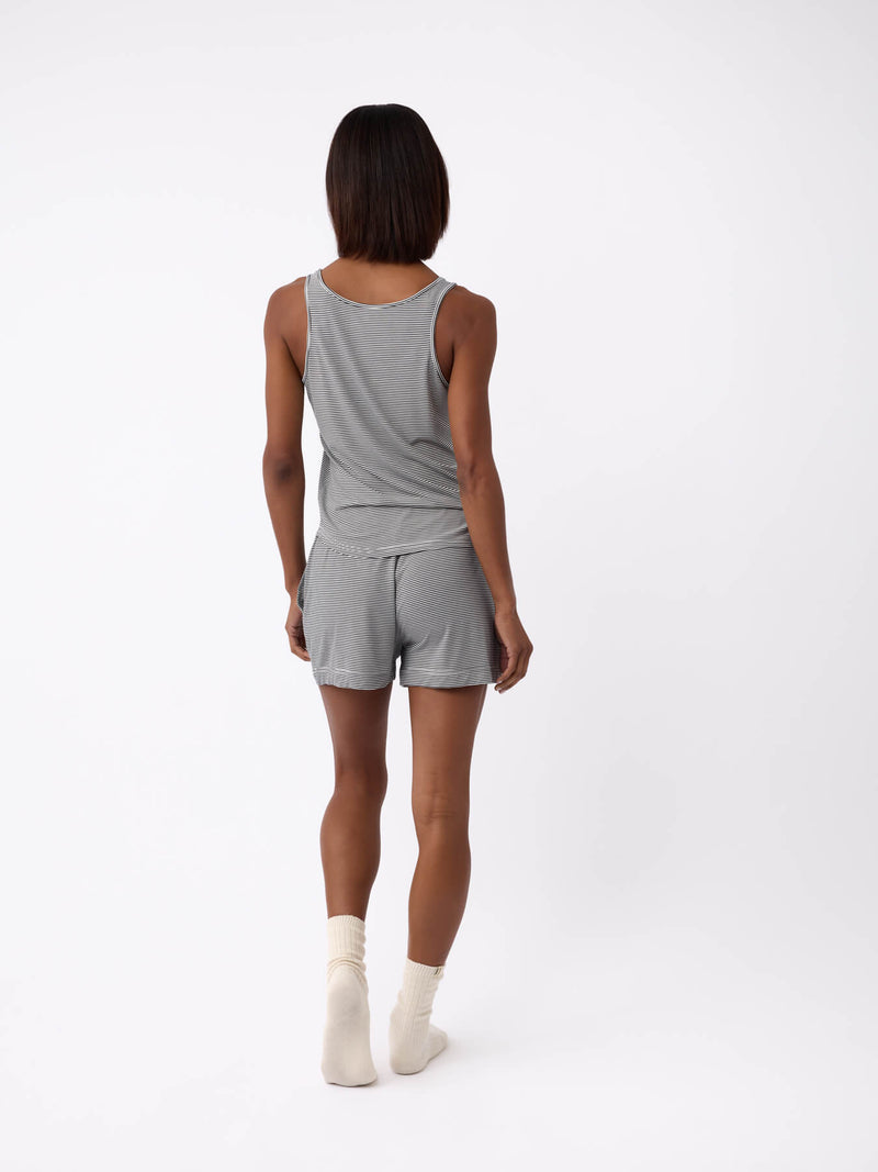 A person stands with their back to the camera, wearing a Cozy Earth Women's Bamboo Stretch-Knit Lounge Tank in gray, paired with matching shorts and white socks, set against a plain white background.