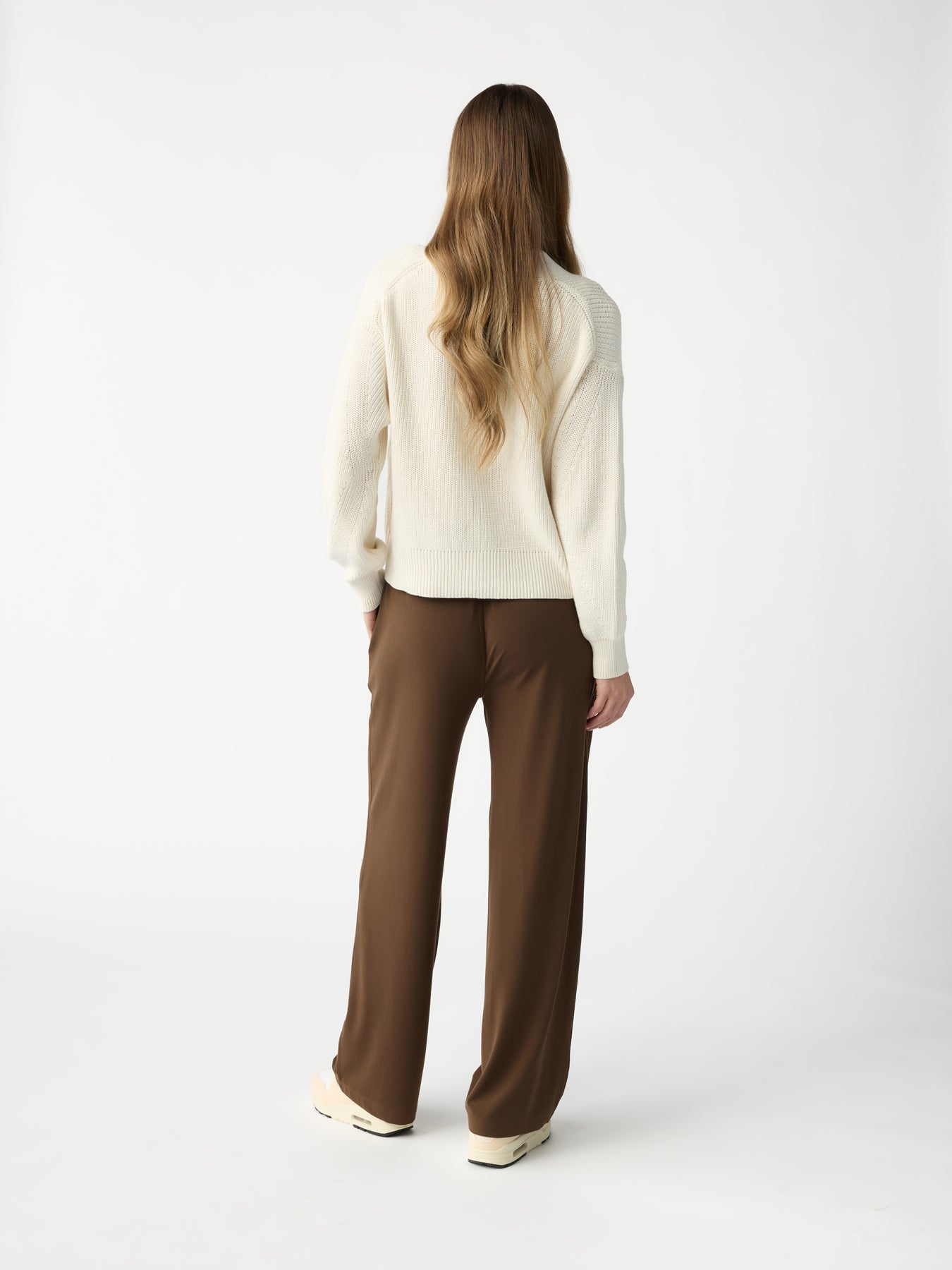 A person with long hair stands facing away, dressed in a cream sweater and Cozy Earth's Women's Studio Wide Leg Pant, set against a plain white background. |Color:Espresso