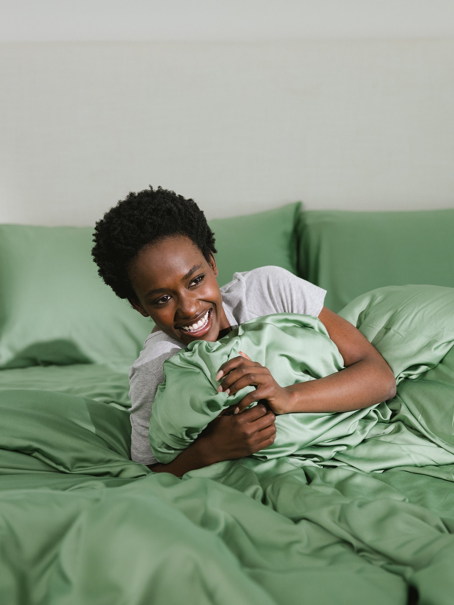 Fern Sheets on bed. A woman rests on the bed. 
