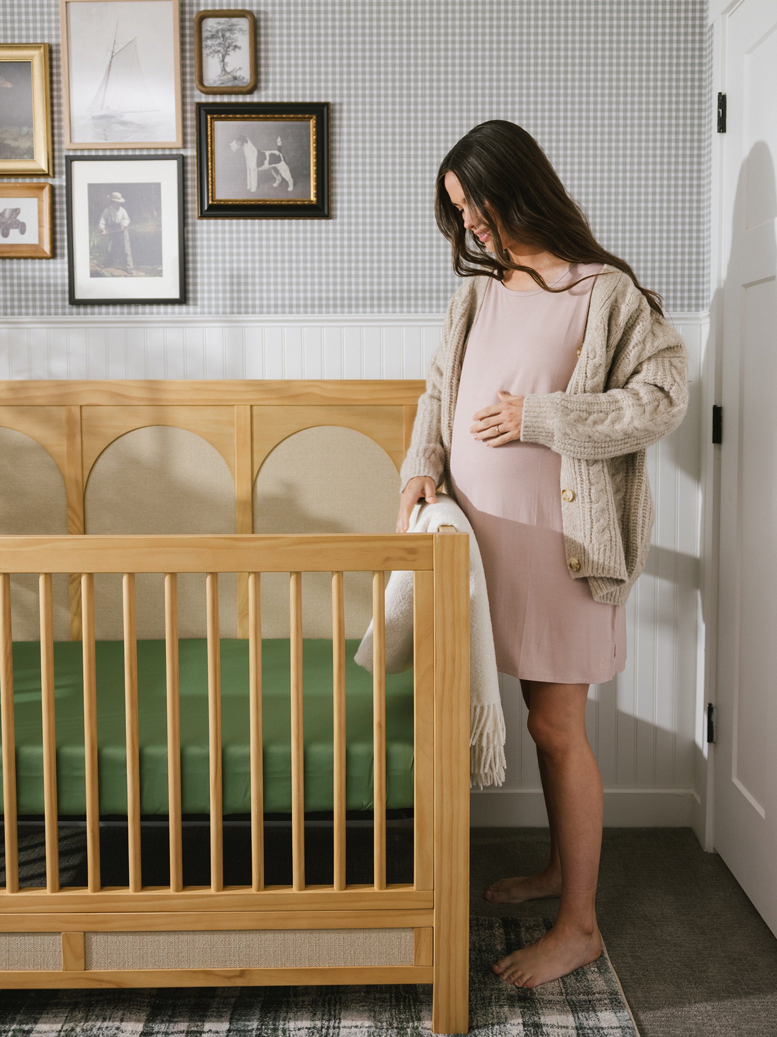 Fern Bamboo Crib Sheet in baby crib. A woman looks at the crib. 