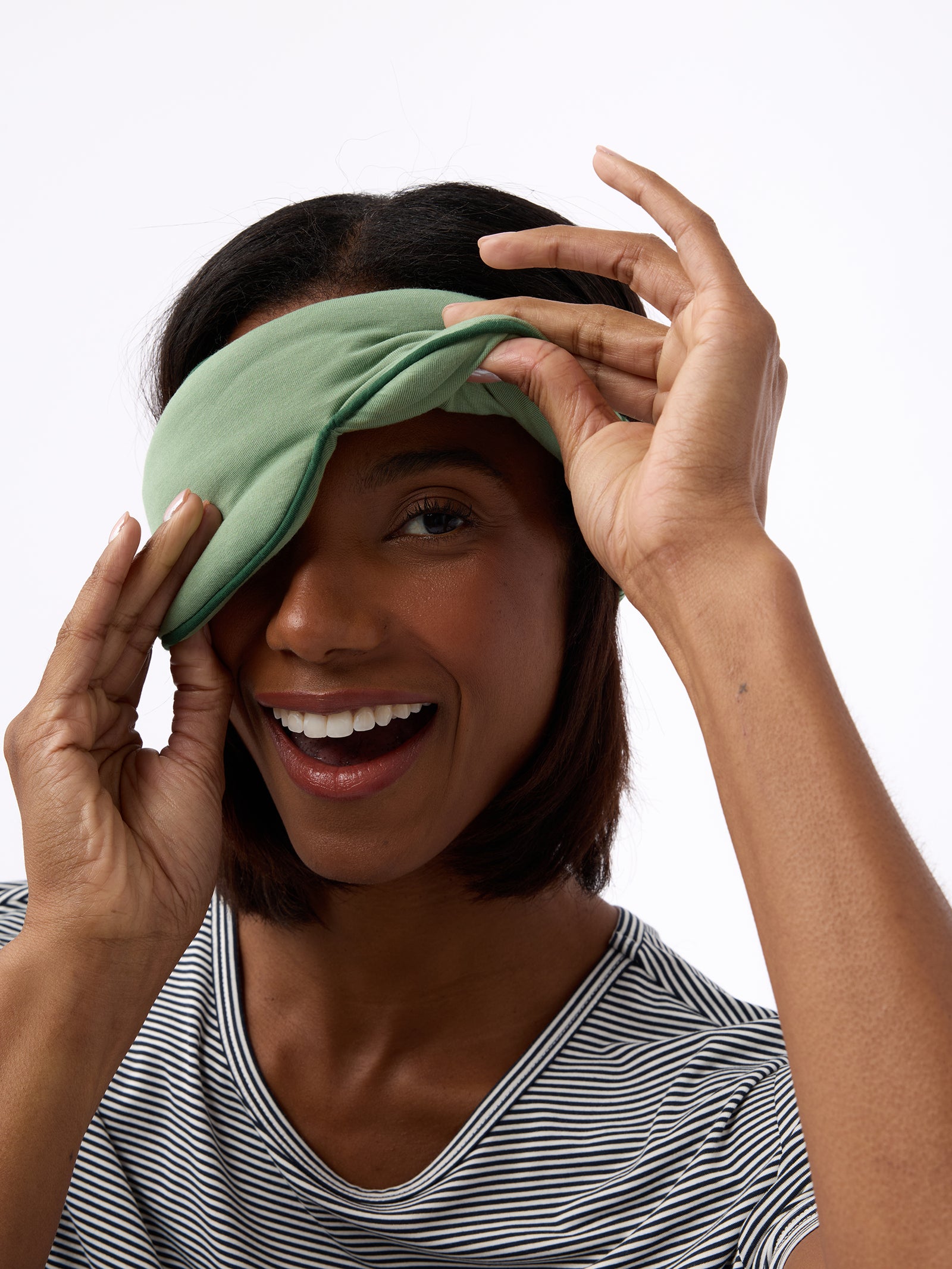 Woman smiling wearing fern sleep mask with one eye revealed 