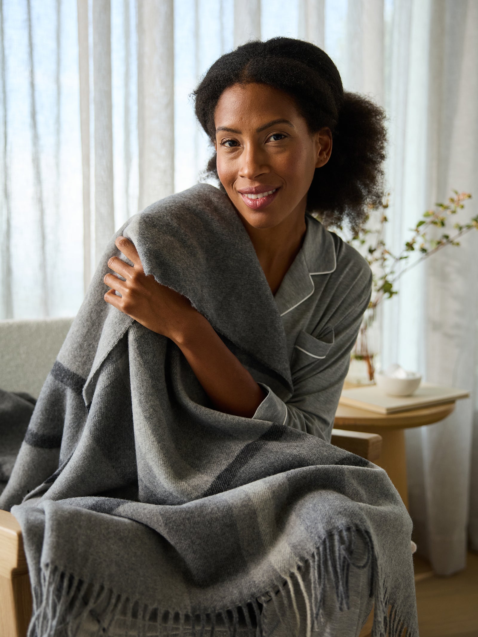 Woman sitting on chair with lucca throw wrapped around her 