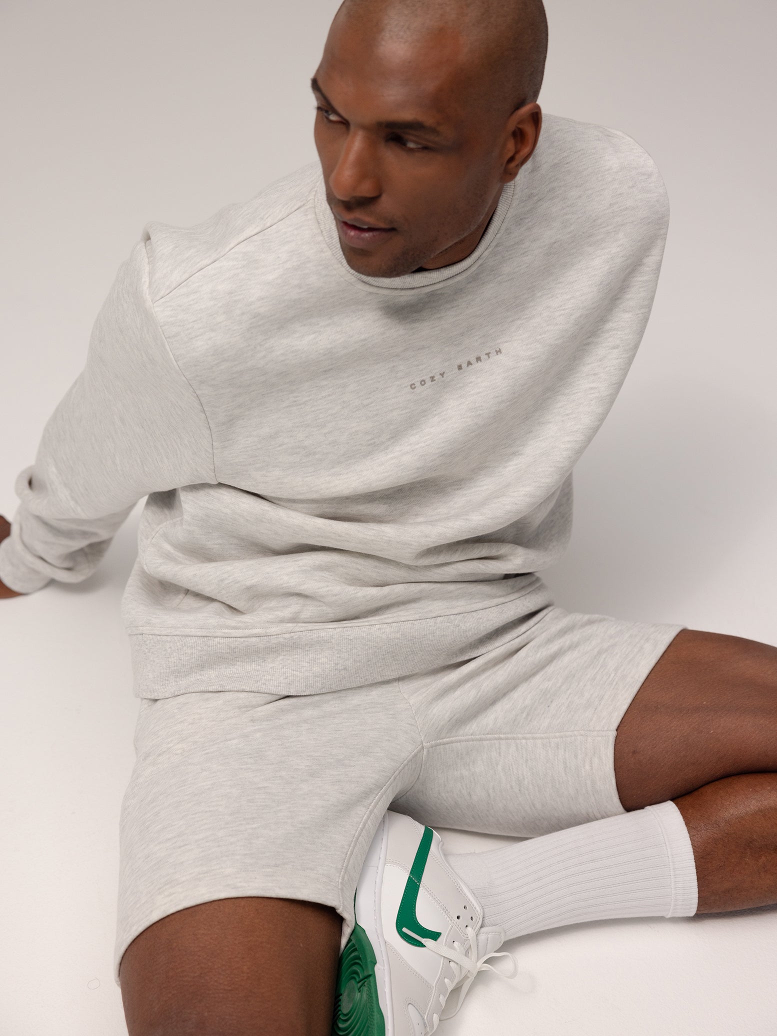Man sitting on ground wearing heather grey cityscape pullover and shorts 