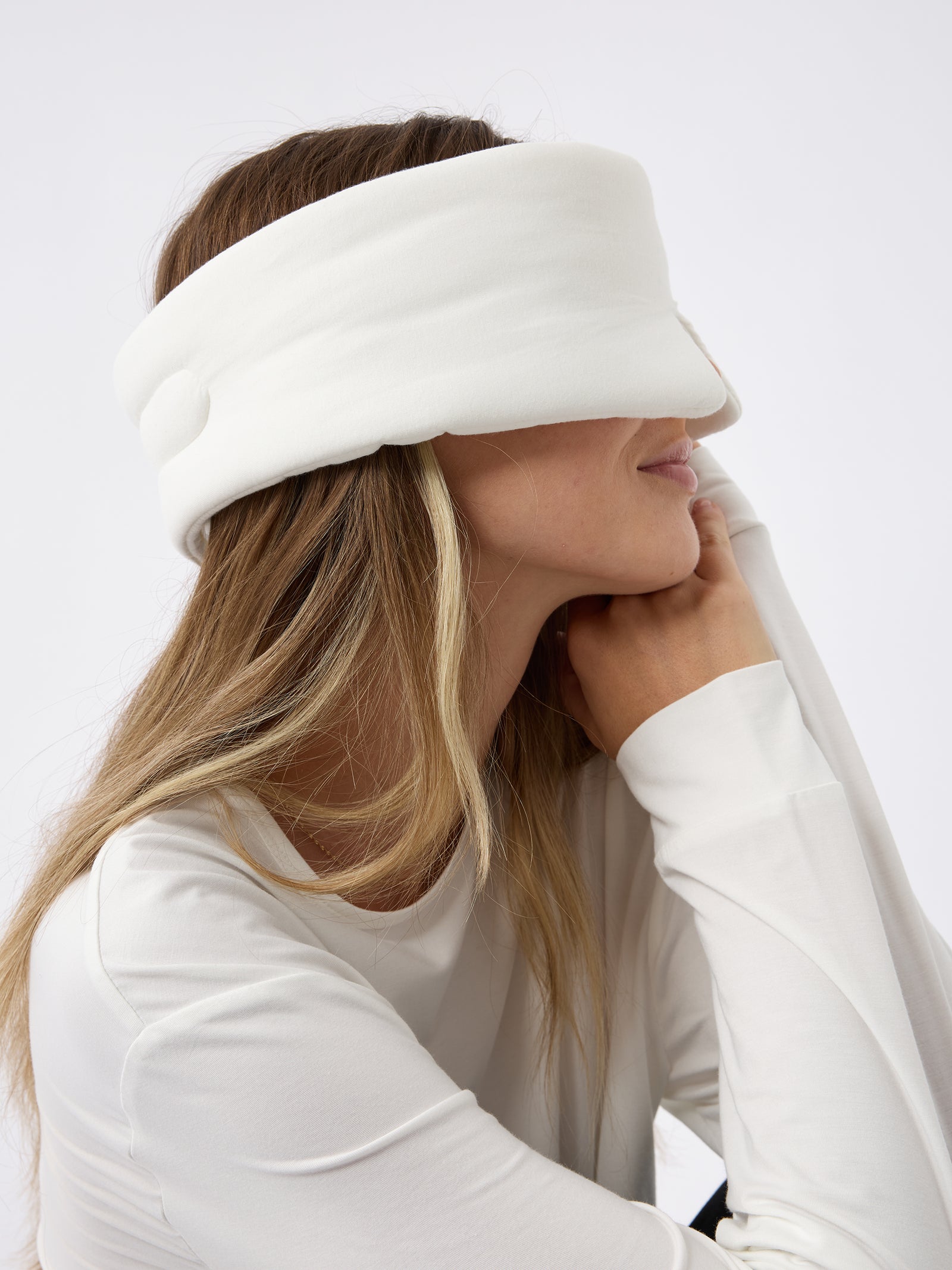 A woman turned to the side wears the Cozy Earth Adjustable Bamboo Sleep Mask in Ivory. 