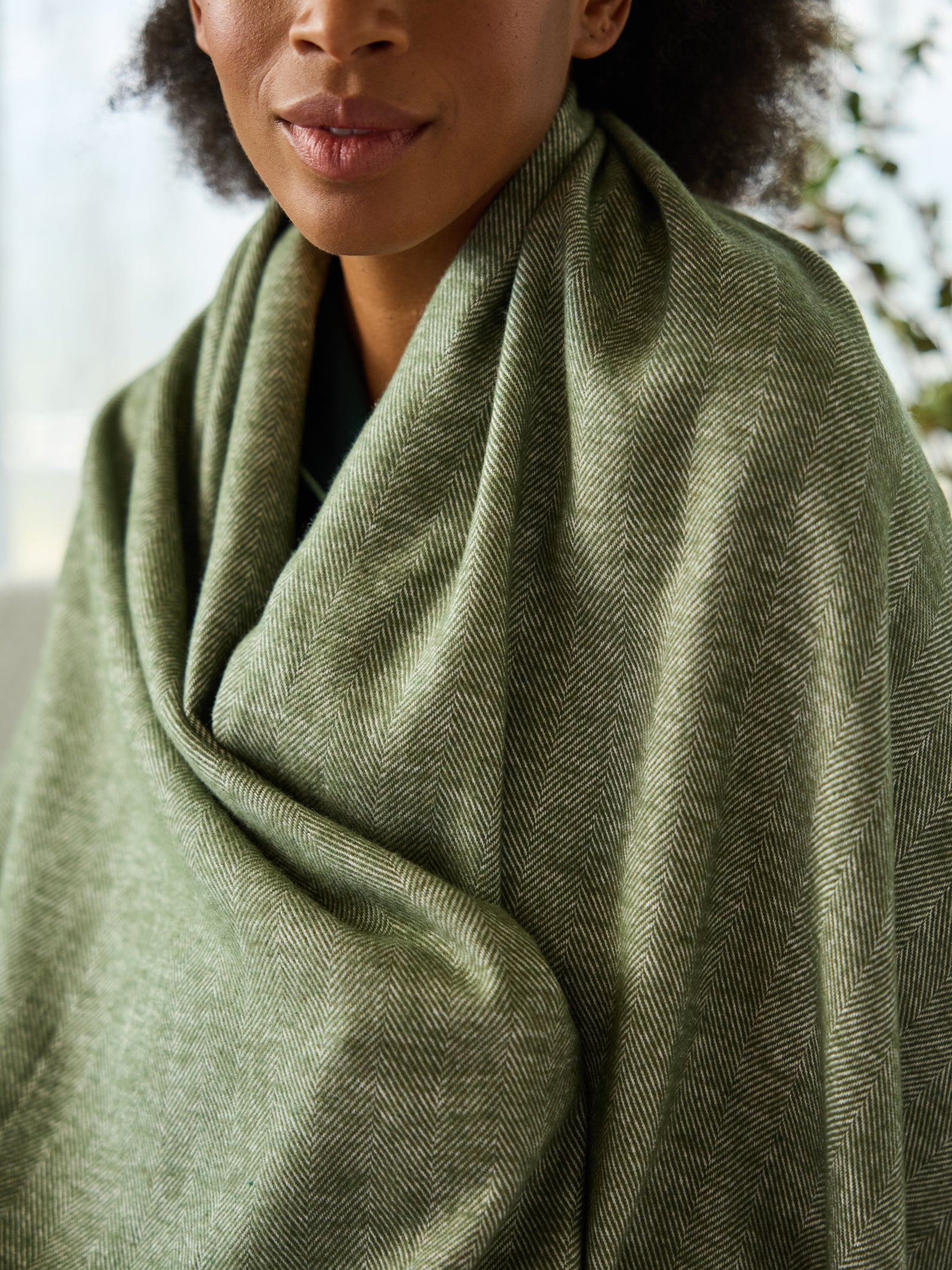 Close up of woman with ivy herringbone tassel throw wrapped around her 