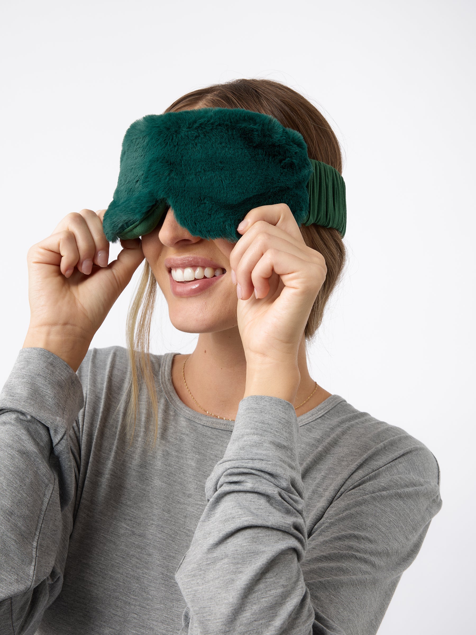 A woman wears the Cozy Earth Faux Fur Sleep Mask in Jade. |Color:Jade 