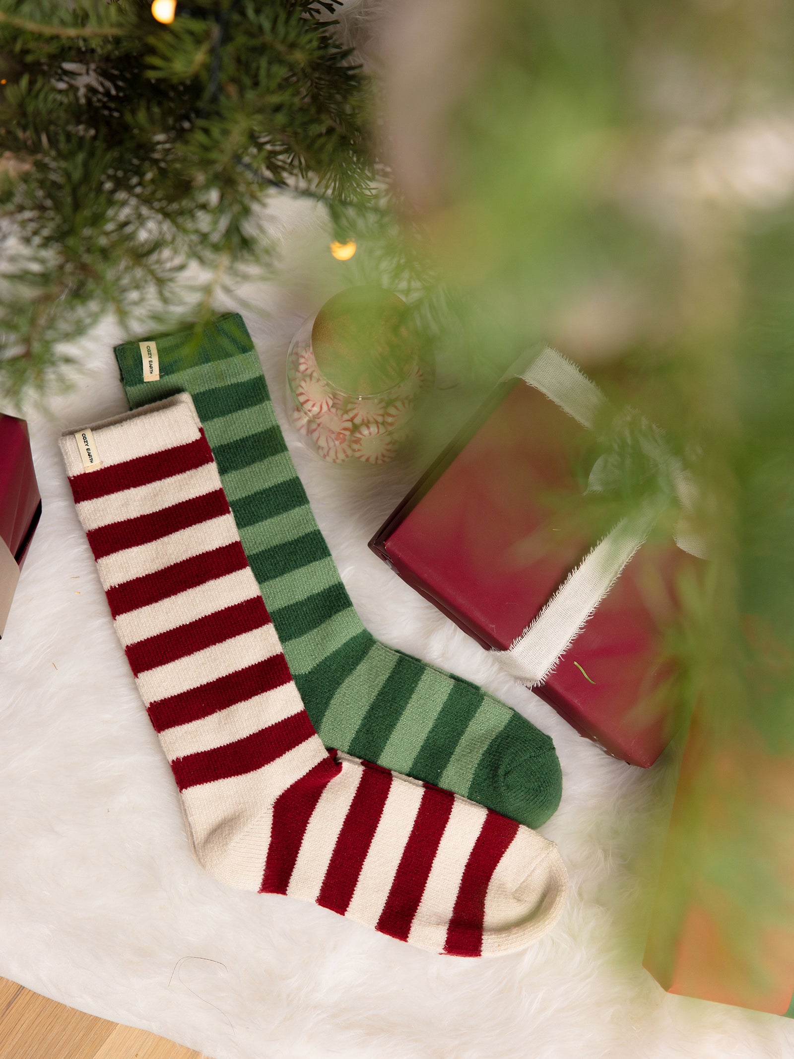 Striped Plush Lounge Socks in Jade and Garnet lying under a Christmas Tree 