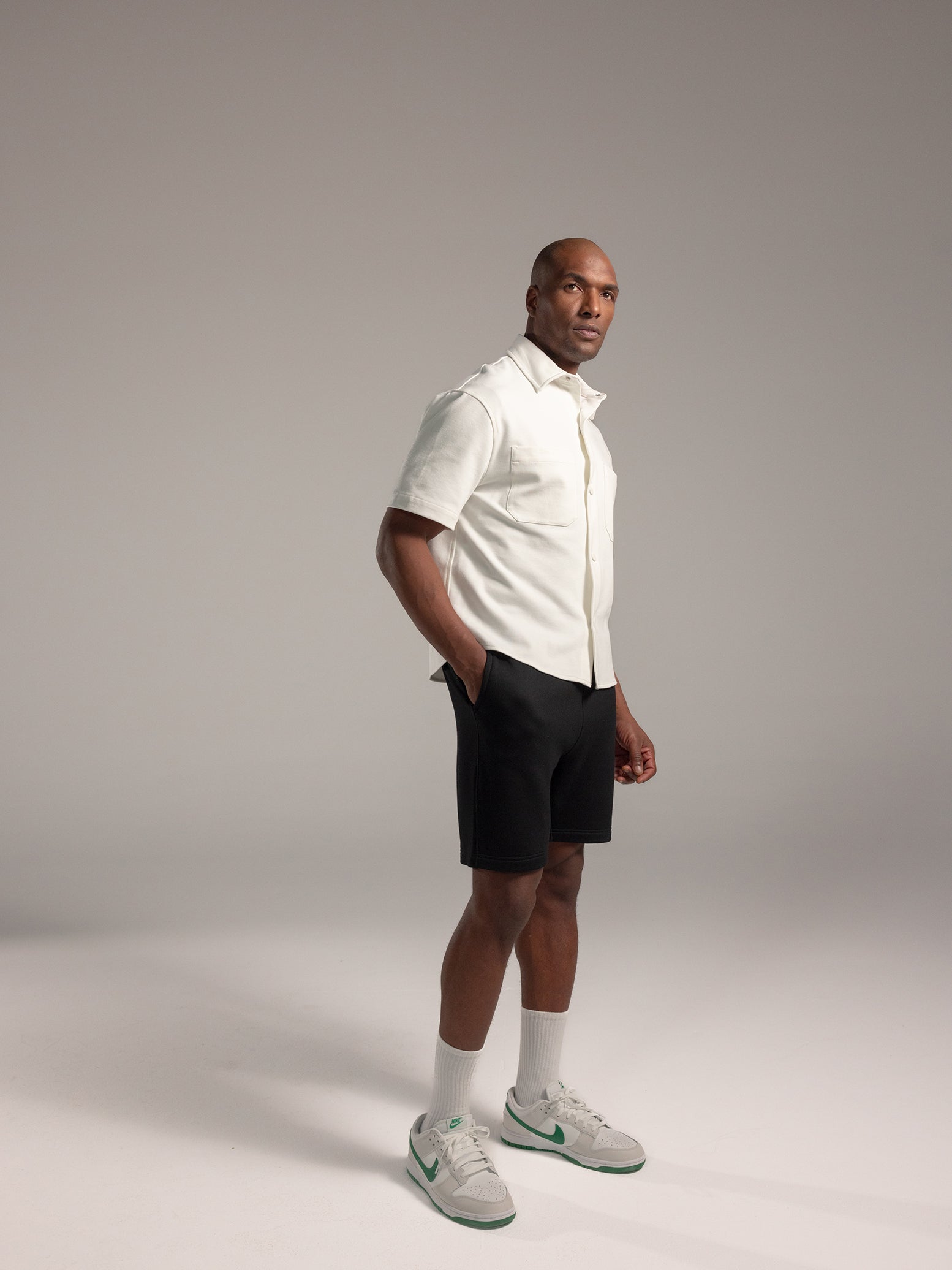 Man wearing white button down and black cityscape shorts 