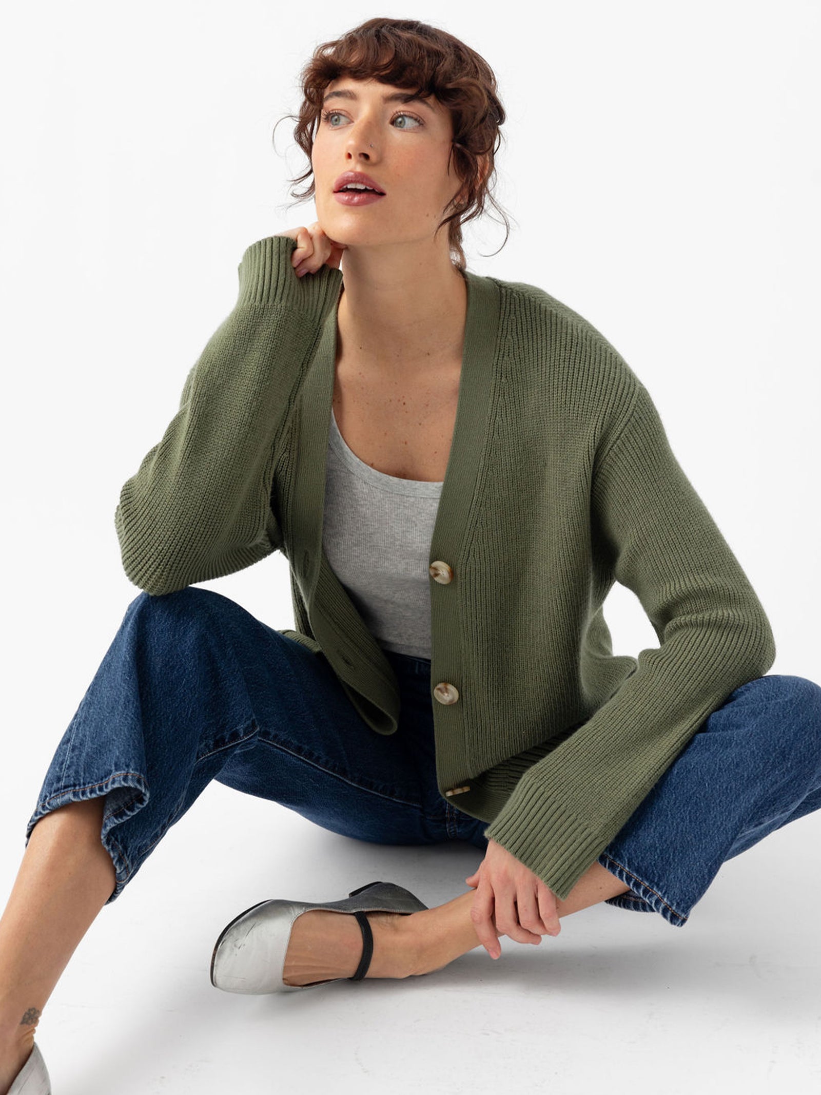 Woman sitting on floor in jeans and juniper cardigan 