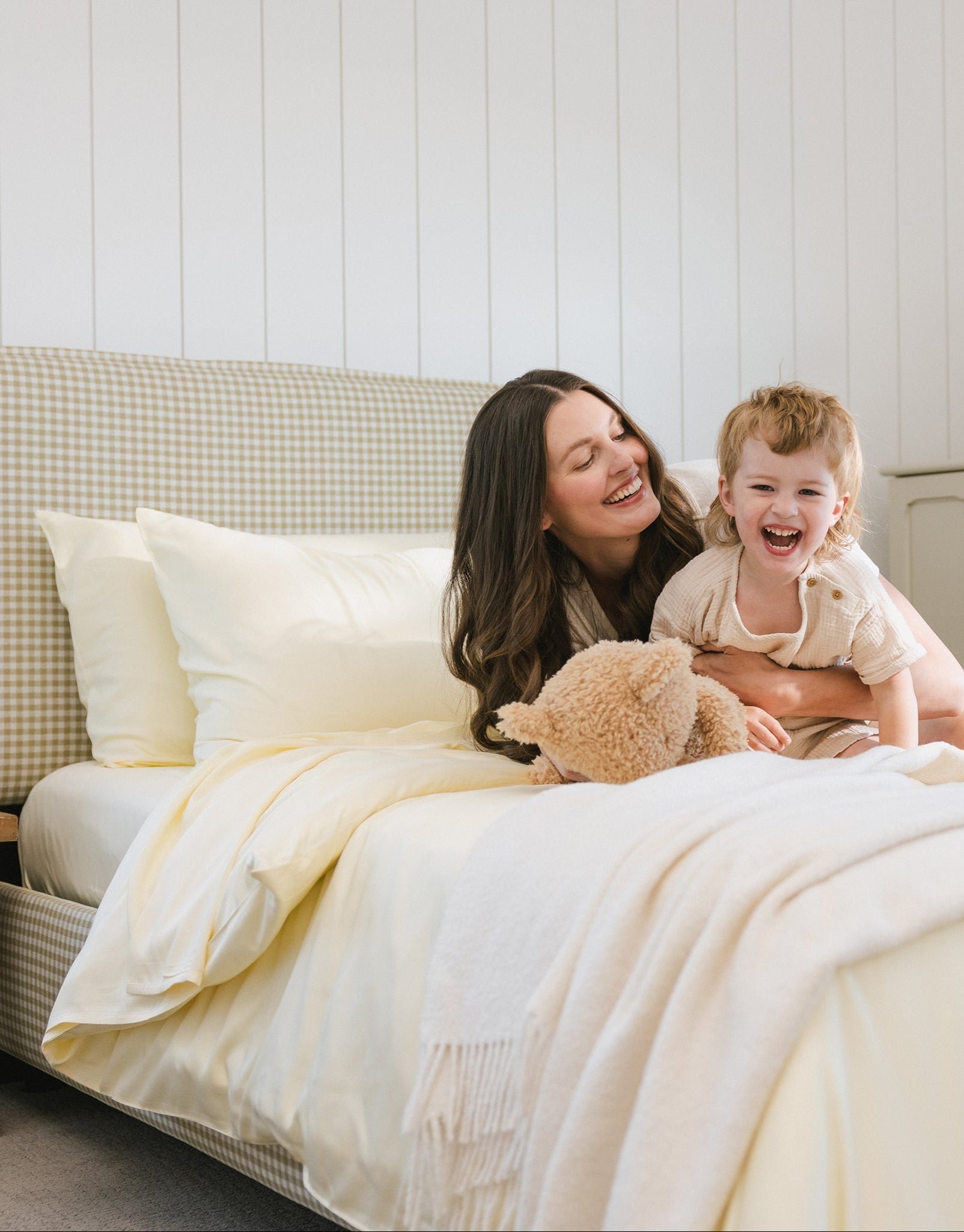 Lemonade Sheets on bed. A woman lays on the bed with her kid. 