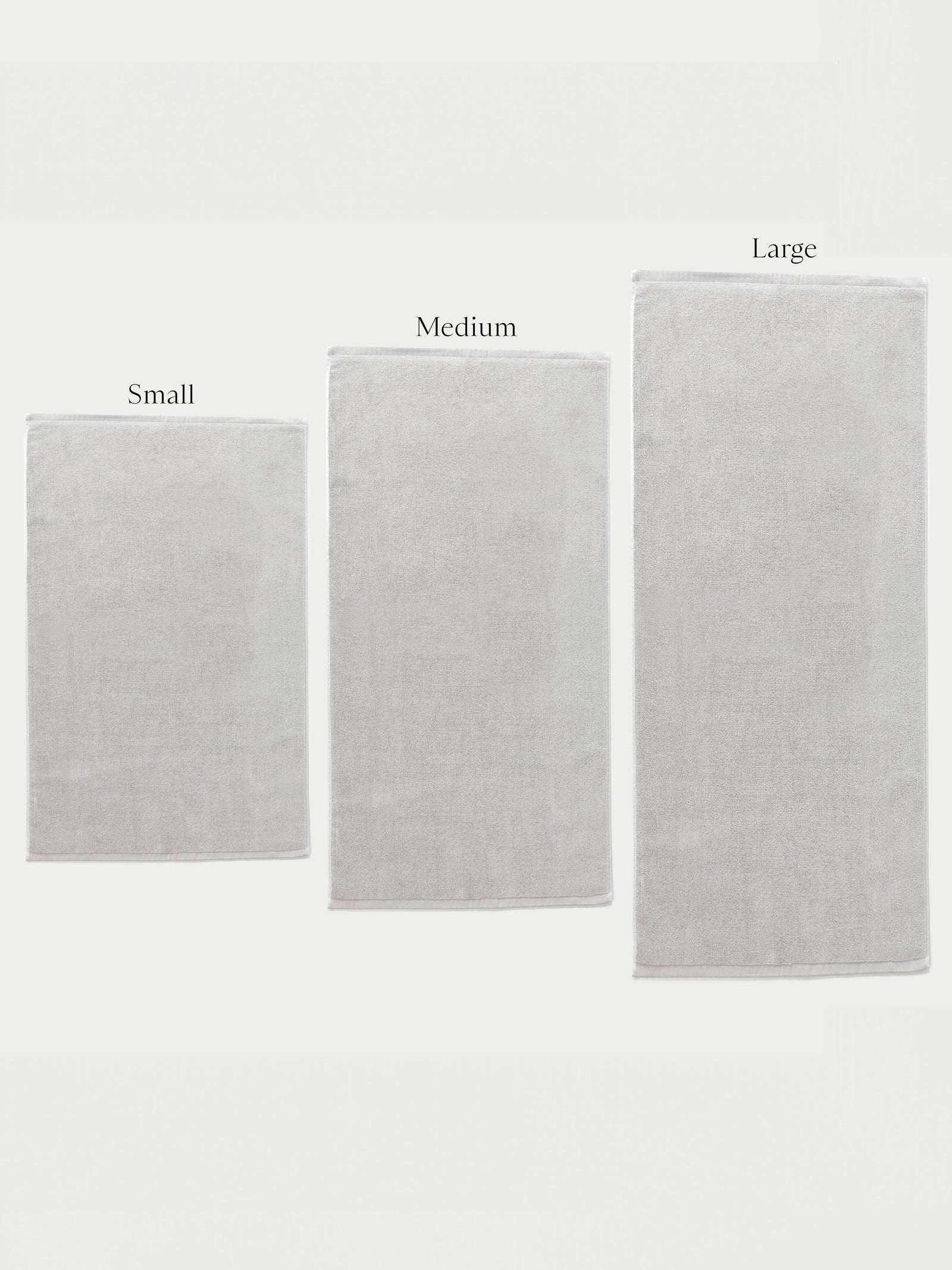 Over a white background rest all three sizes of bath mat. The labels "Small", "Medium", and "Large" are labeled over the bath mats.