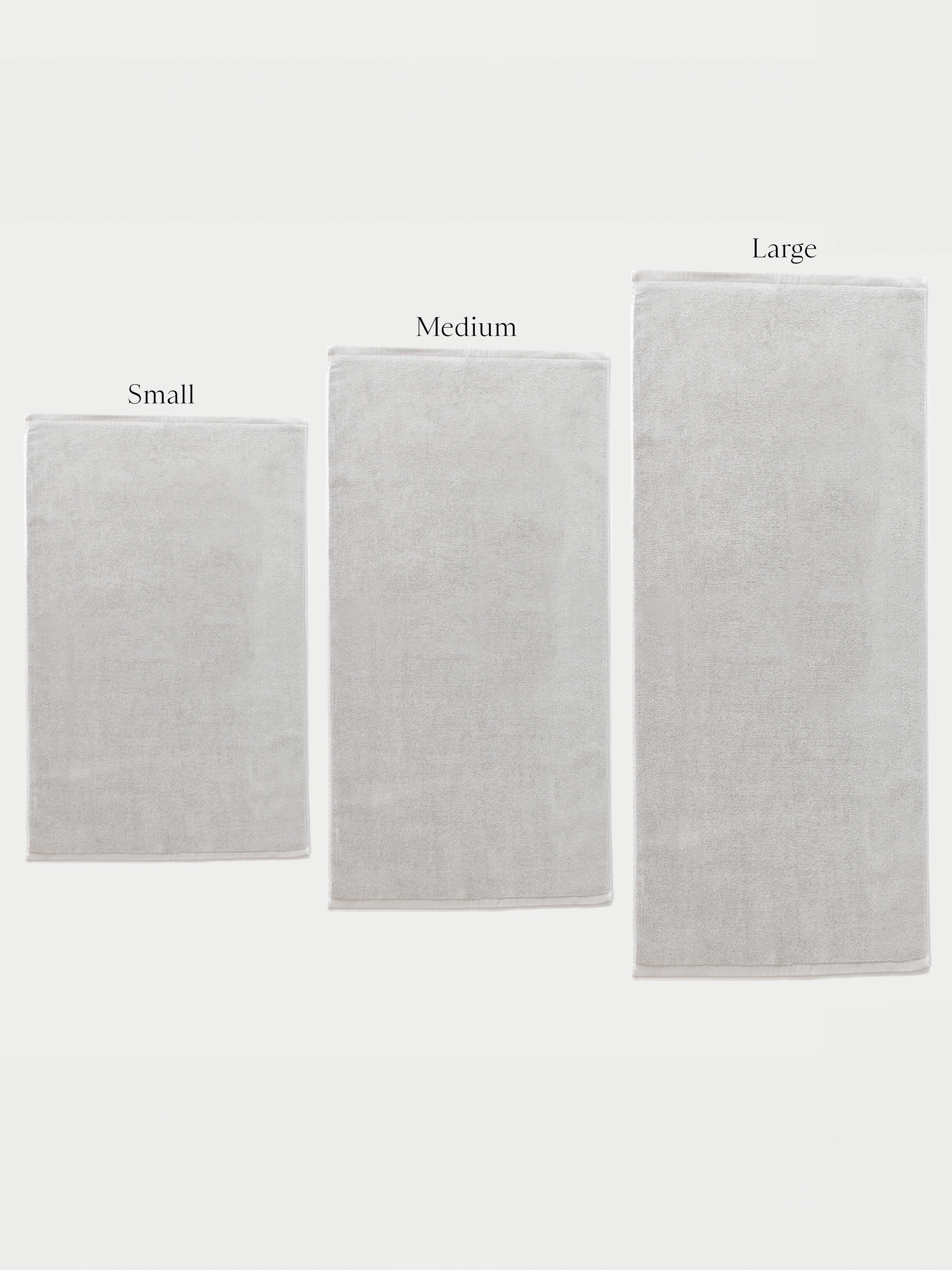 All three sizes of light grey bath mat. The labels "Small", "Medium", and "Large" are labeled over the bath mats. Light Grey.