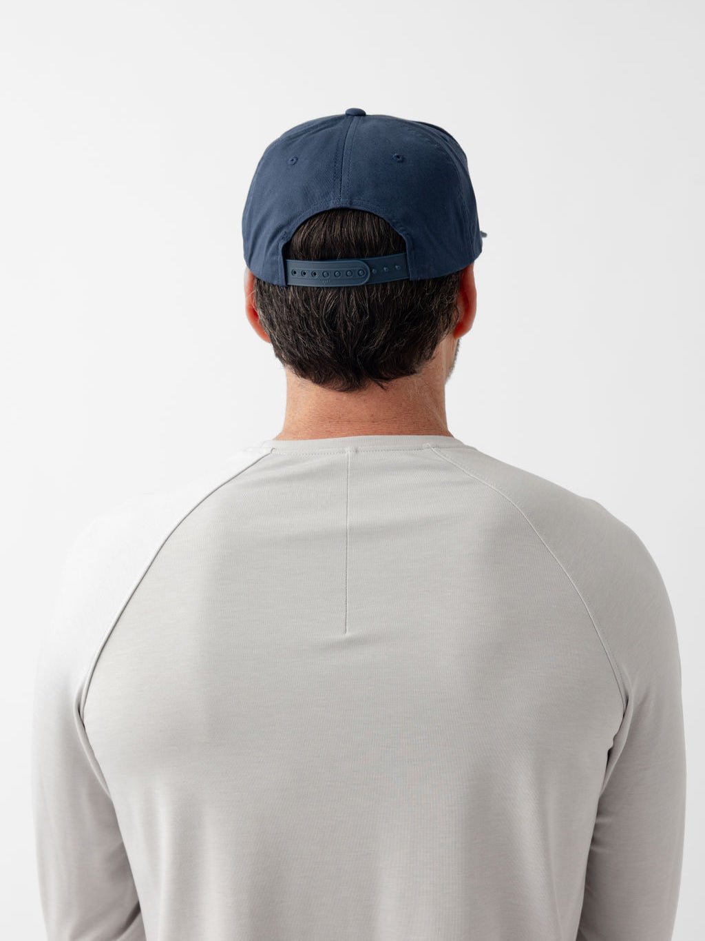 Back of man wearing navy heritage snapback 