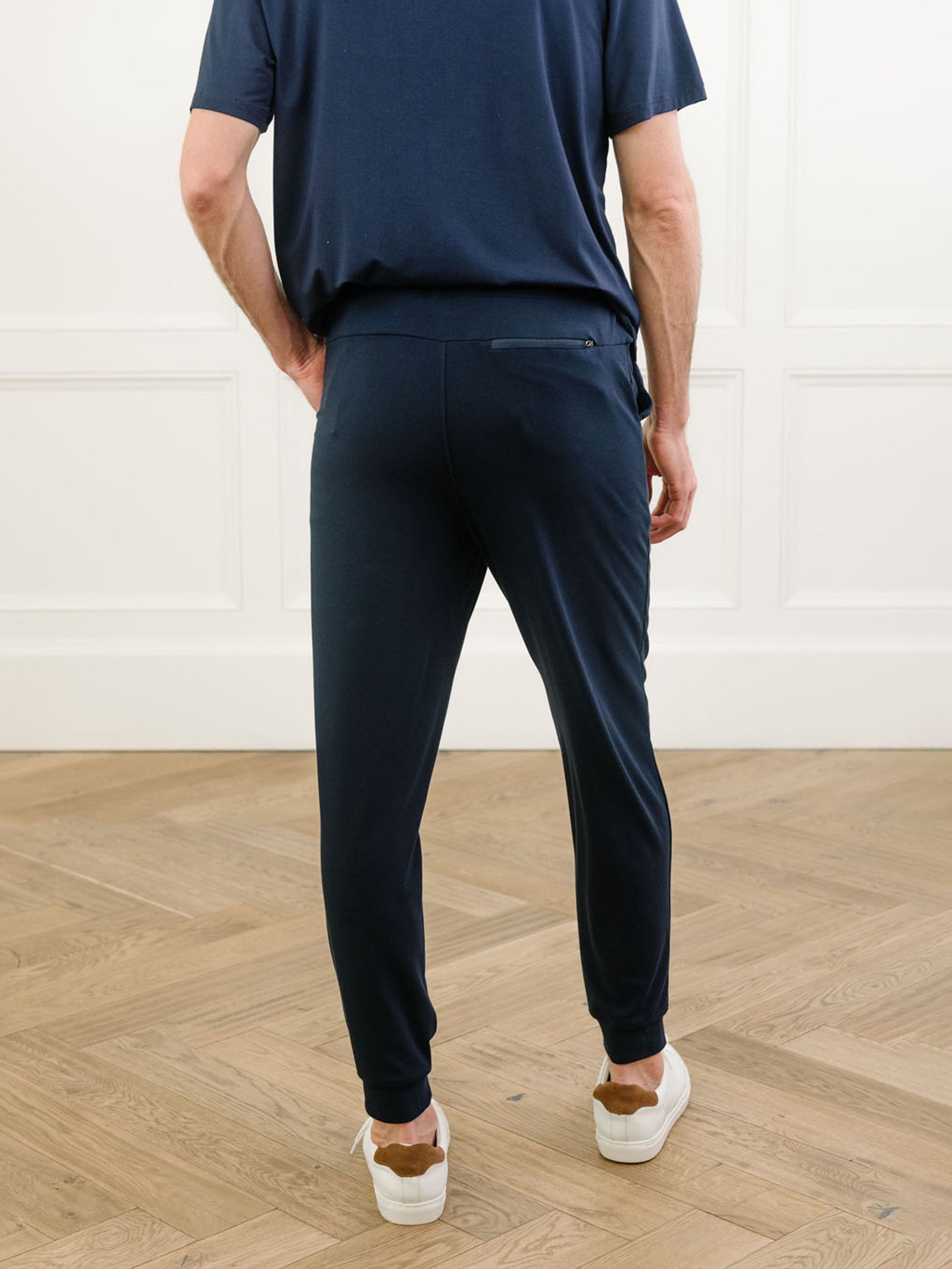 Navy Men's Bamboo Jogger Set. There is a man wearing the jogger set. He is standing in a well lit room in a home.