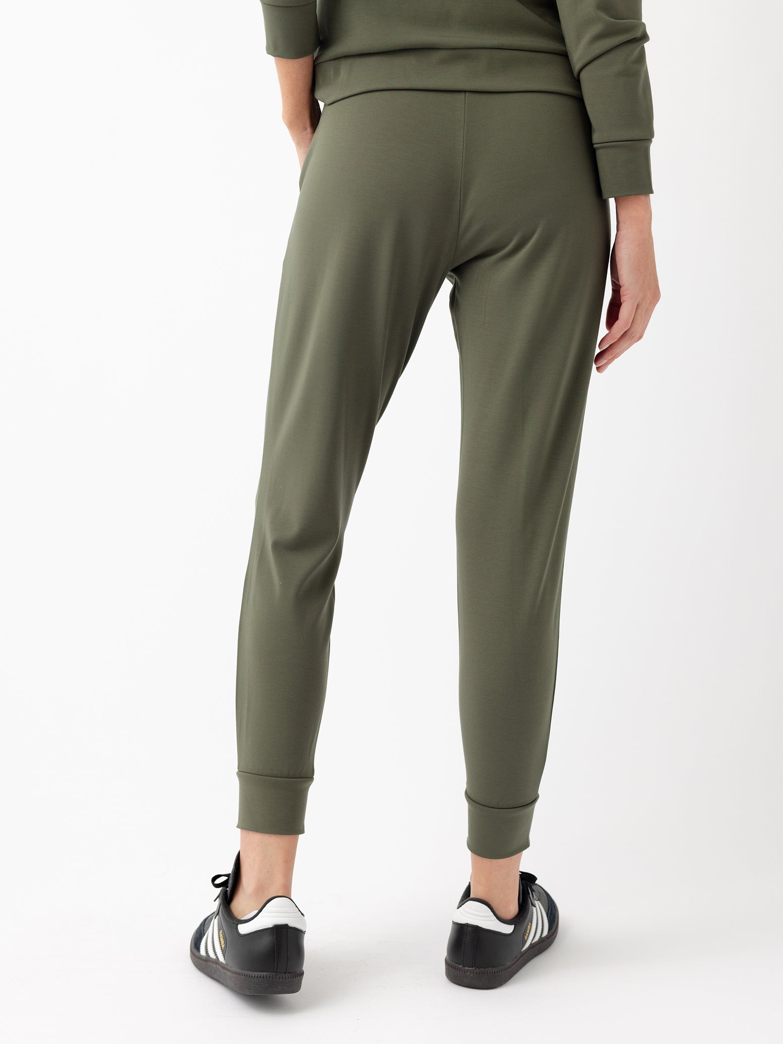 Back of woman in olive joggers with white background 