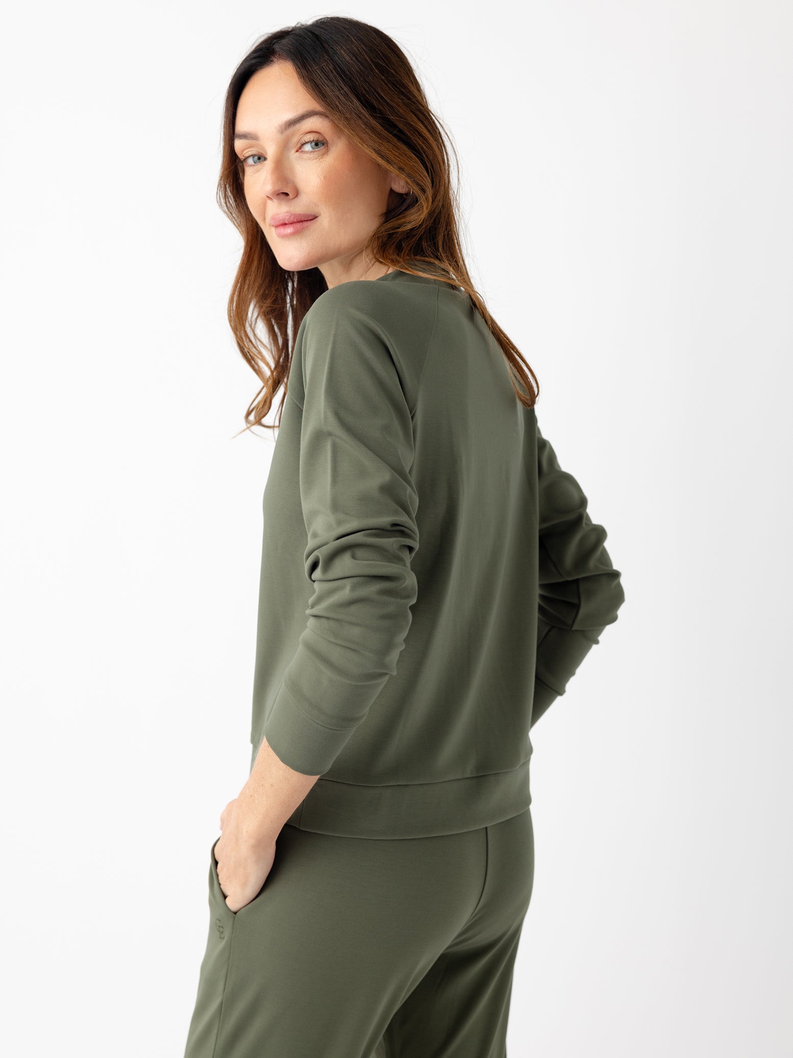 Back of woman in olive crewneck with white background 