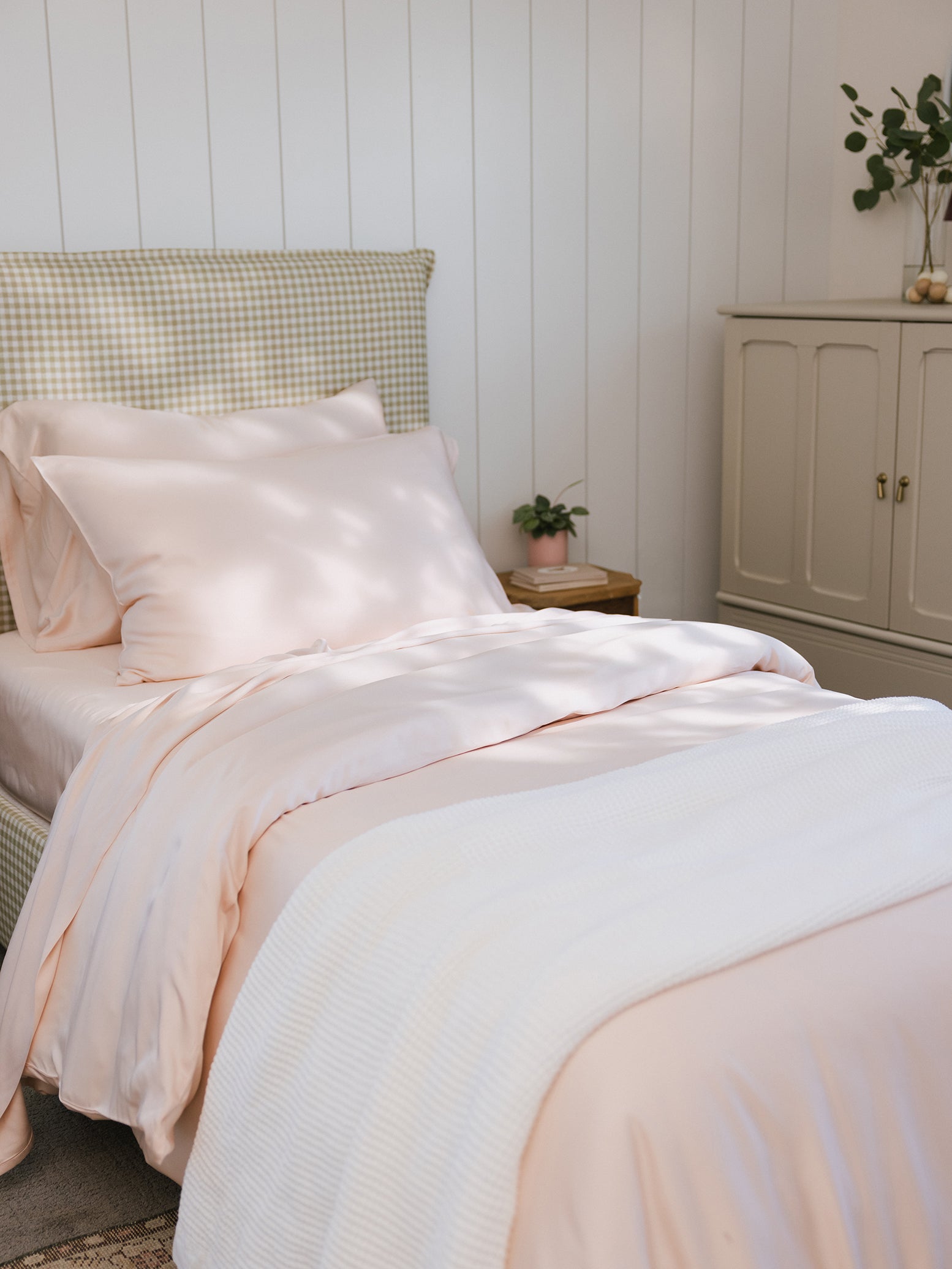 Bed with peony bedding and white throw blanket on top 