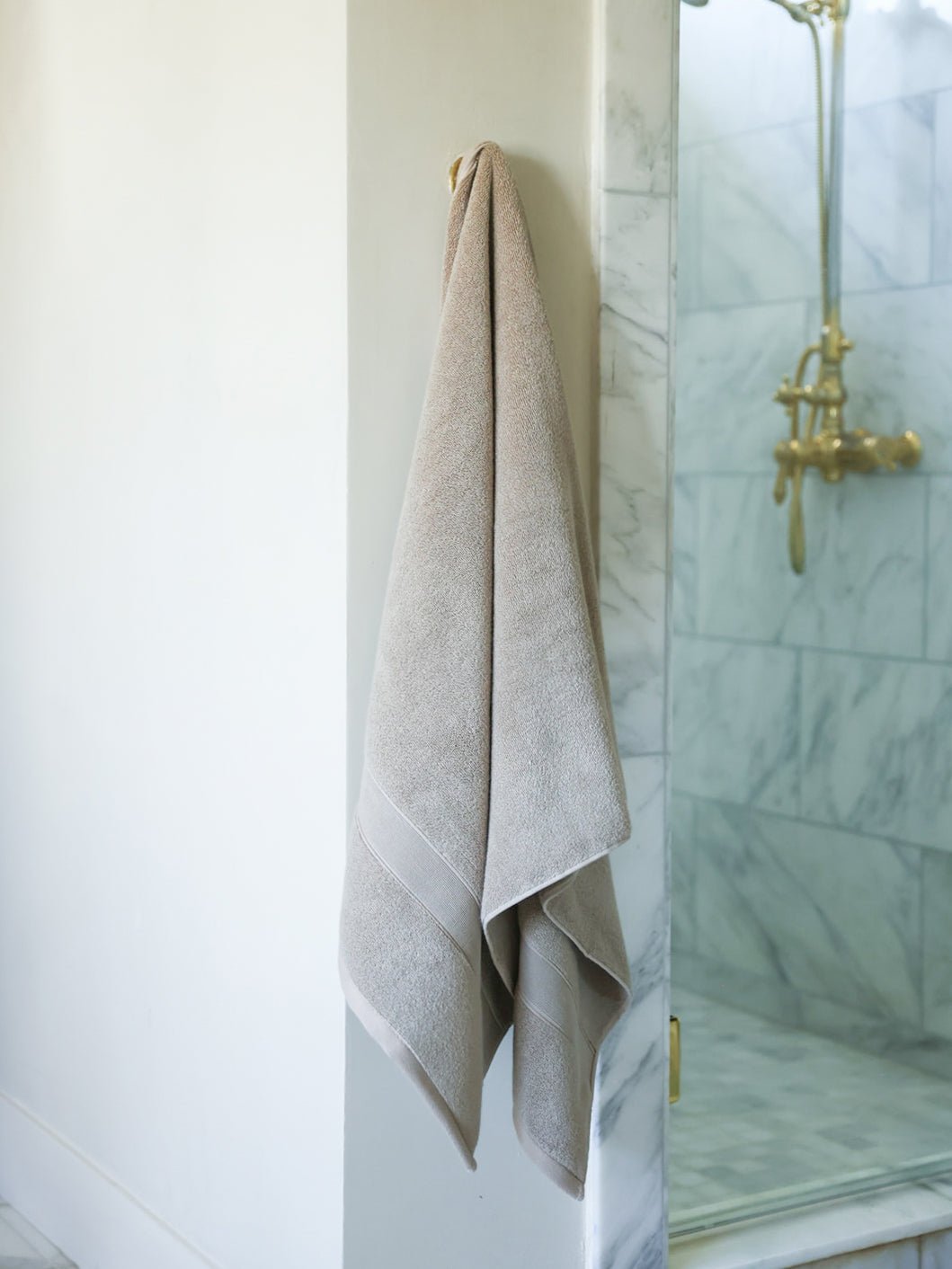 Sand luxe bath sheet hanging next to shower 