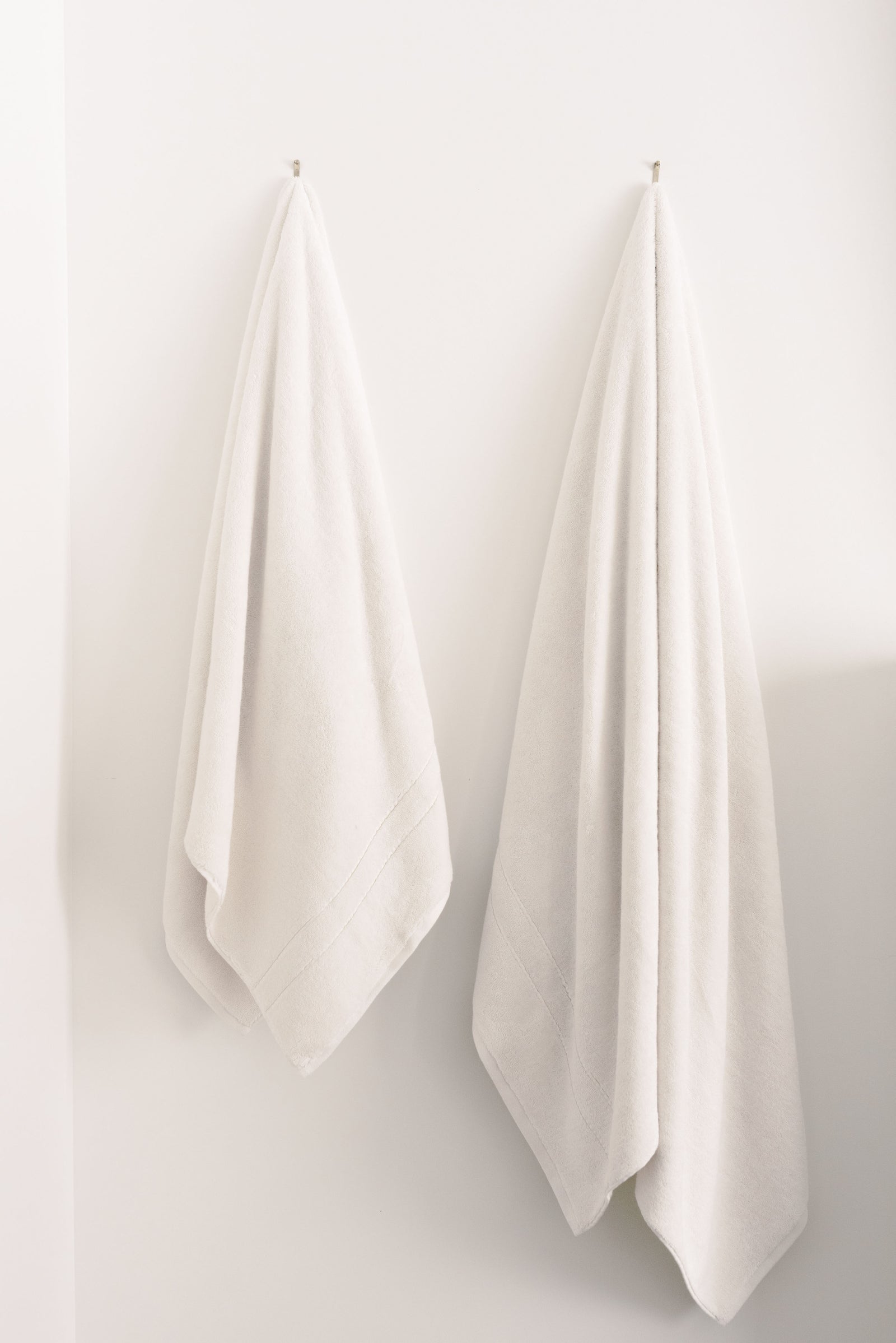 Premium Plush Bath Towels/sheets in the color seashell. Photo of Premium Plush Bath Towels taken in a bathroom showing the towels which are hung from a towel rack. 