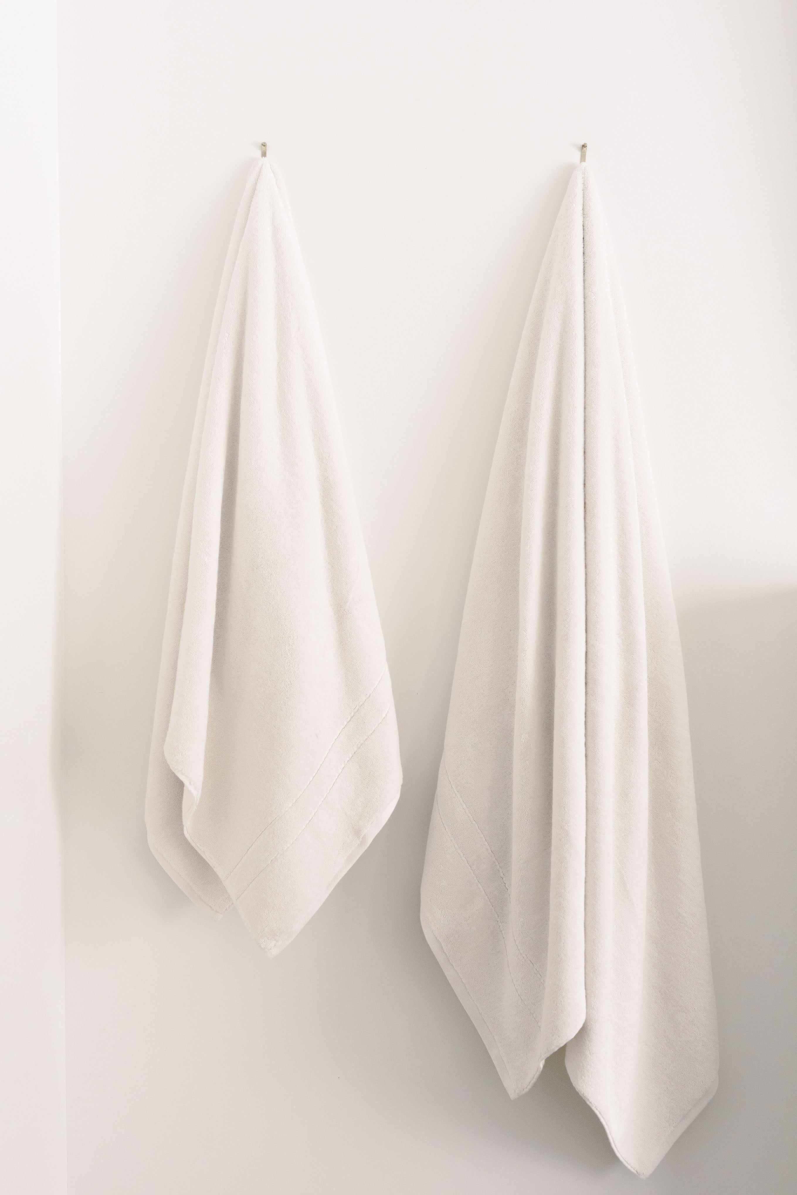 Premium Plush Bath Towels/sheets in the color seashell. Photo of Premium Plush Bath Towels taken in a bathroom showing the towels which are hung from a towel rack. |Color:Seashell