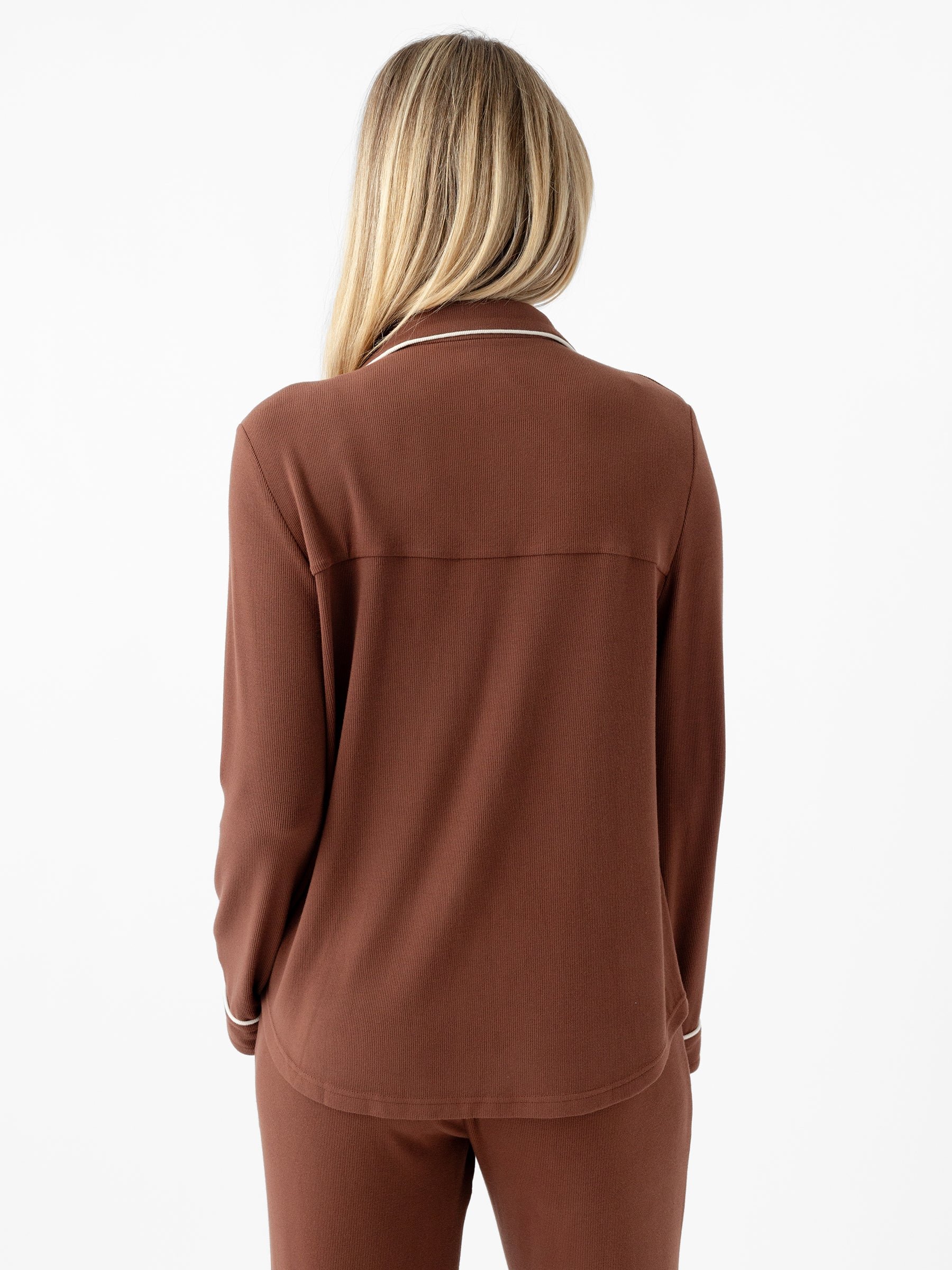 A person with long, blonde hair is facing away from the camera, wearing a Cozy Earth Women's Bamboo Rib Knit Classic Long Sleeve Pajama Top. The image shows them from the back, highlighting the top's simple design and collar. The background is plain white. 