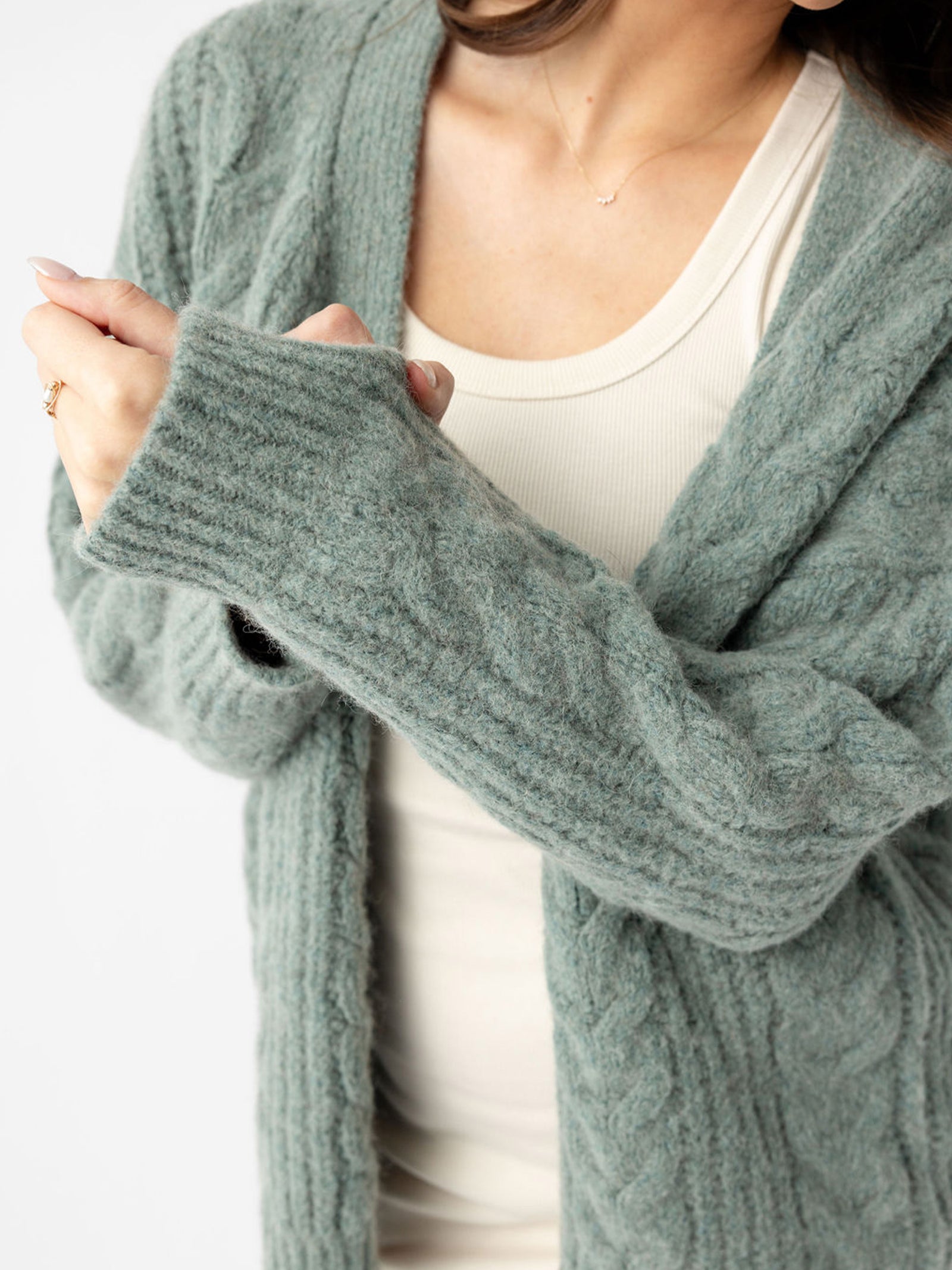 Close up of woman wearing thyme cardigan over off-white dress 