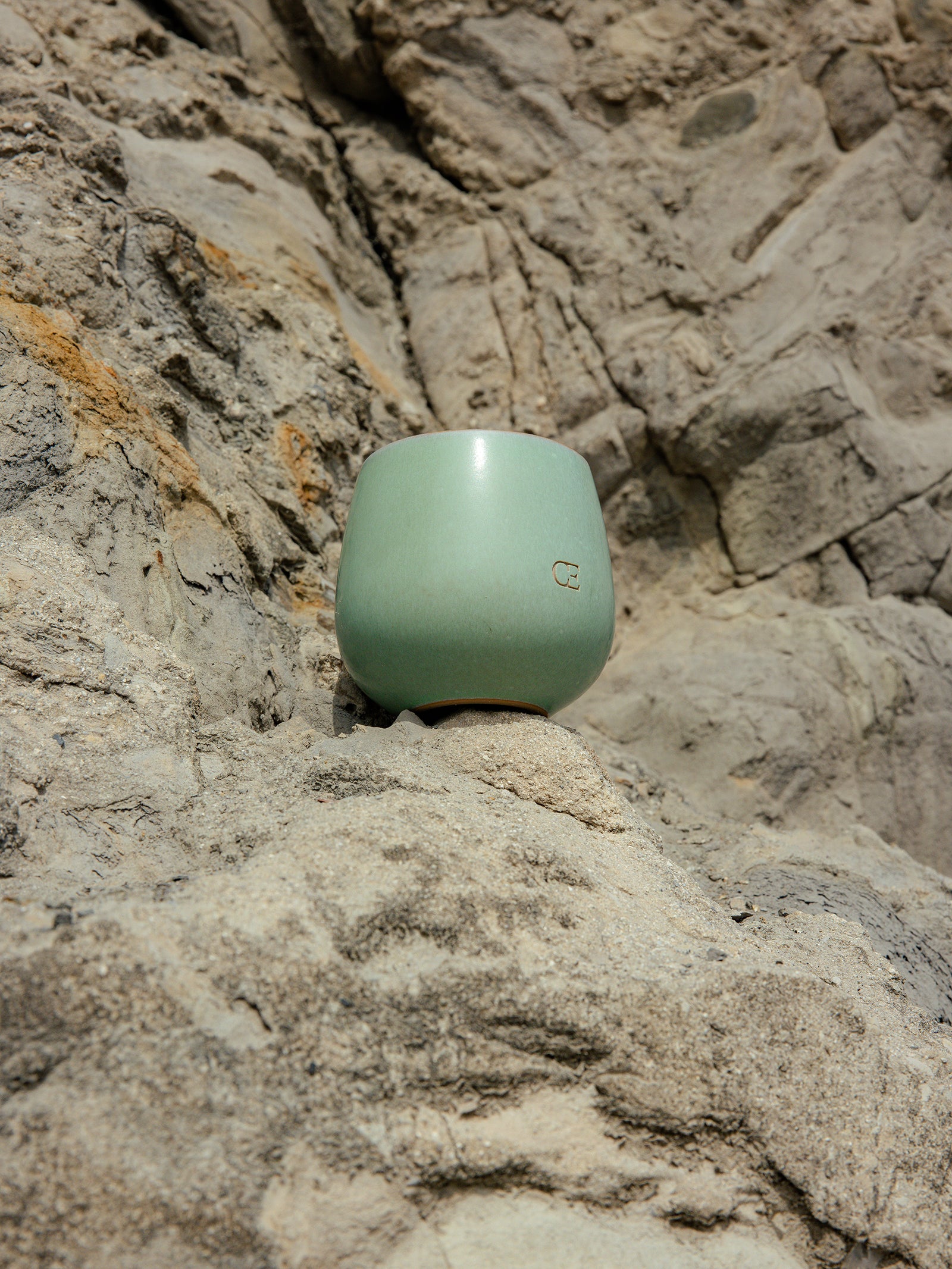 Cozy Earth Unwind Candle placed on a rocky outcropping